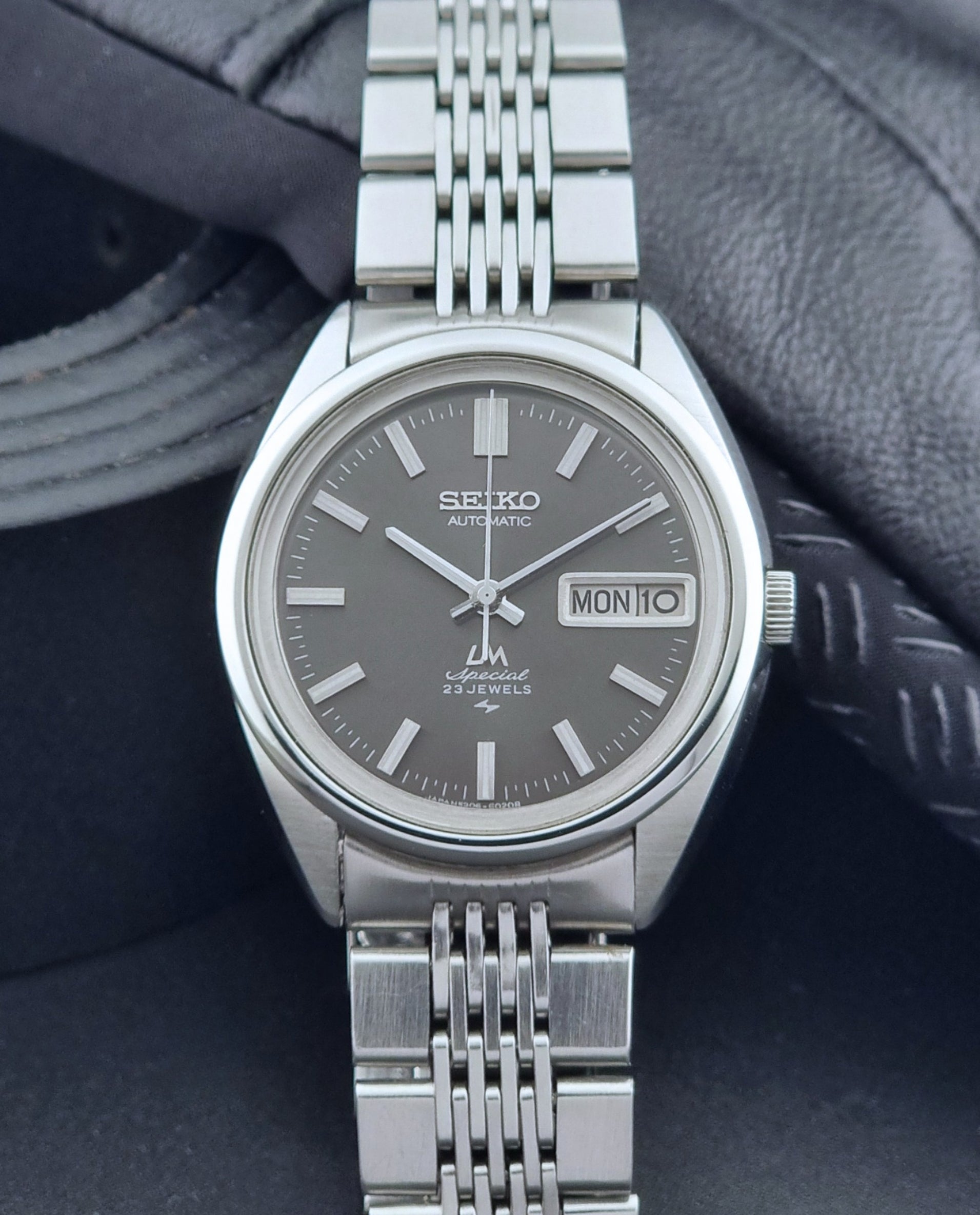 Vintage Seiko LordMatic Special 5206-6021 wristwatch with a dark gray face on a black background front view