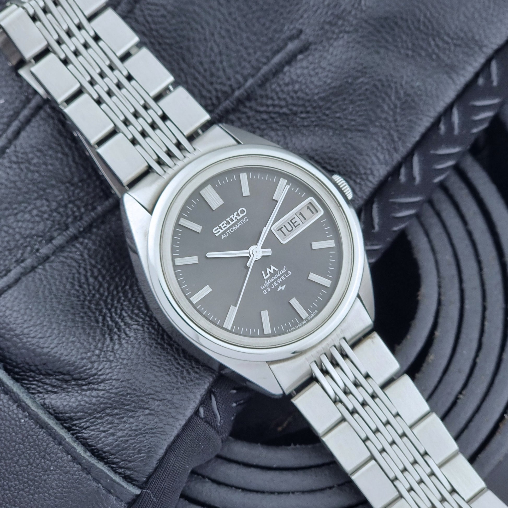 Vintage Seiko LordMatic Special 5206-6021 wristwatch with a dark gray face on a black background front