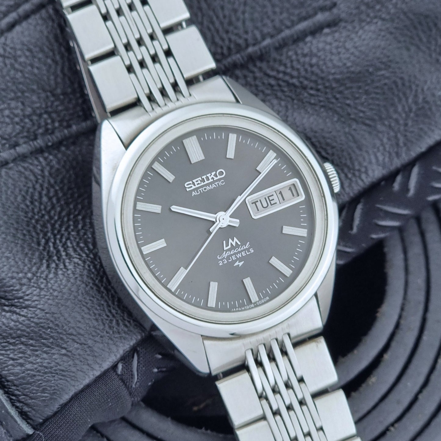 Vintage Seiko LordMatic Special 5206-6021 wristwatch with a dark gray face on a black background dial view