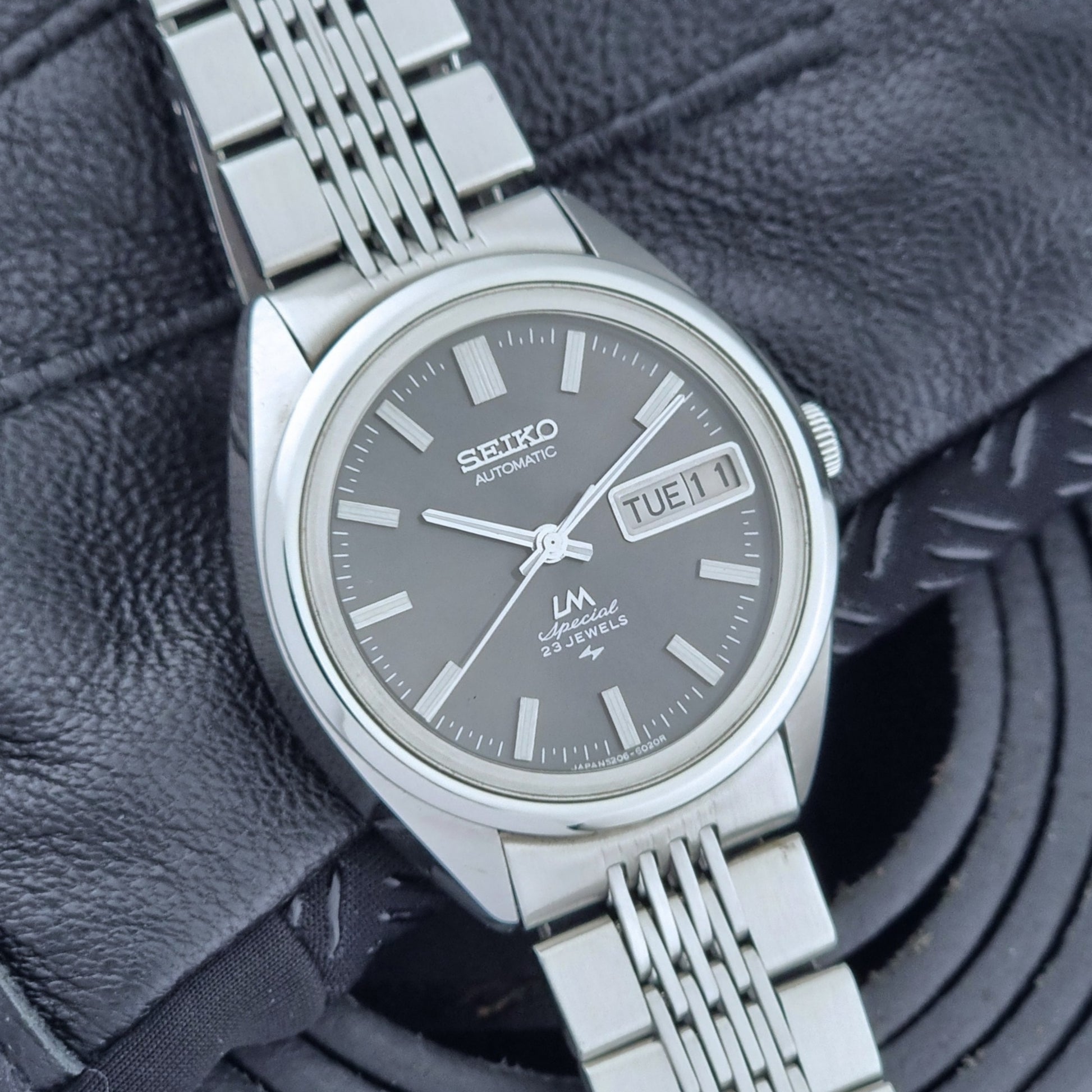 Vintage Seiko LordMatic Special 5206-6021 wristwatch with a dark gray face on a black background dial view