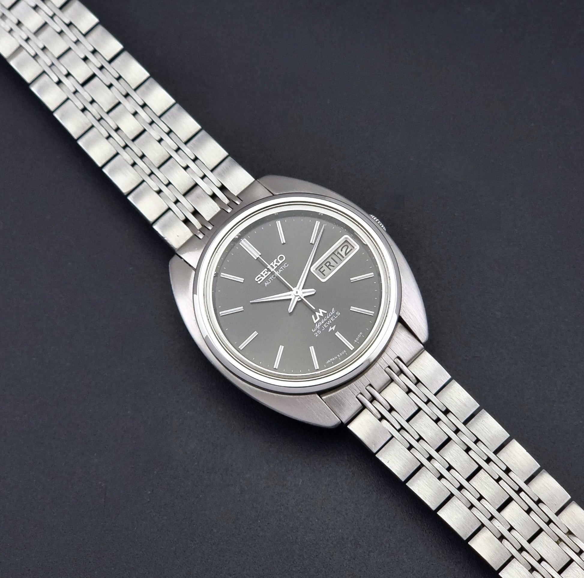 Vintage Seiko watch LordMatic Special 5206-6030 with a stainless steel bracelet on a dark background dial