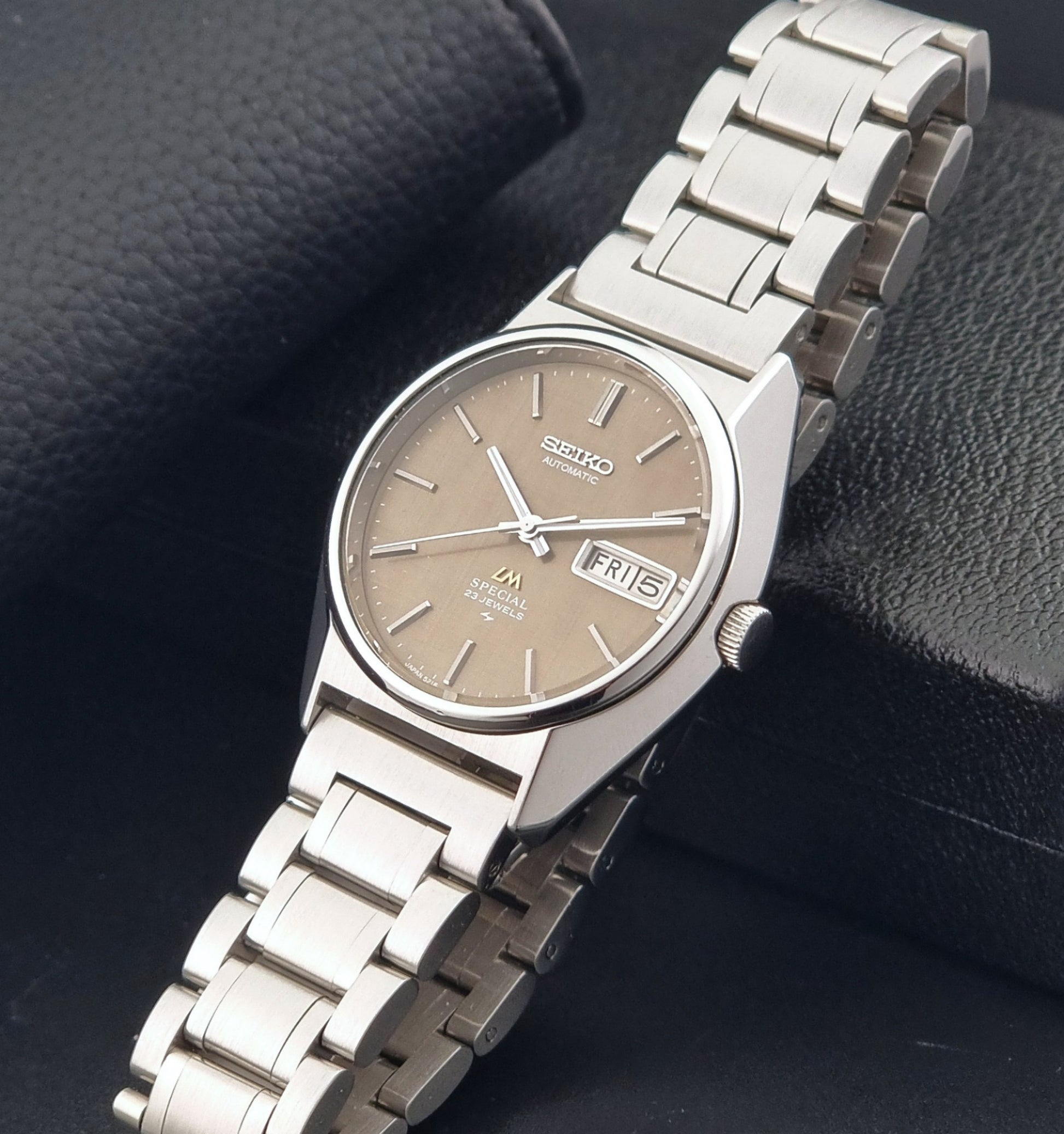 Vintage Seiko Wristwatch LordMatic Special 5216-8020 with a brown dial on a dark gray background crown view