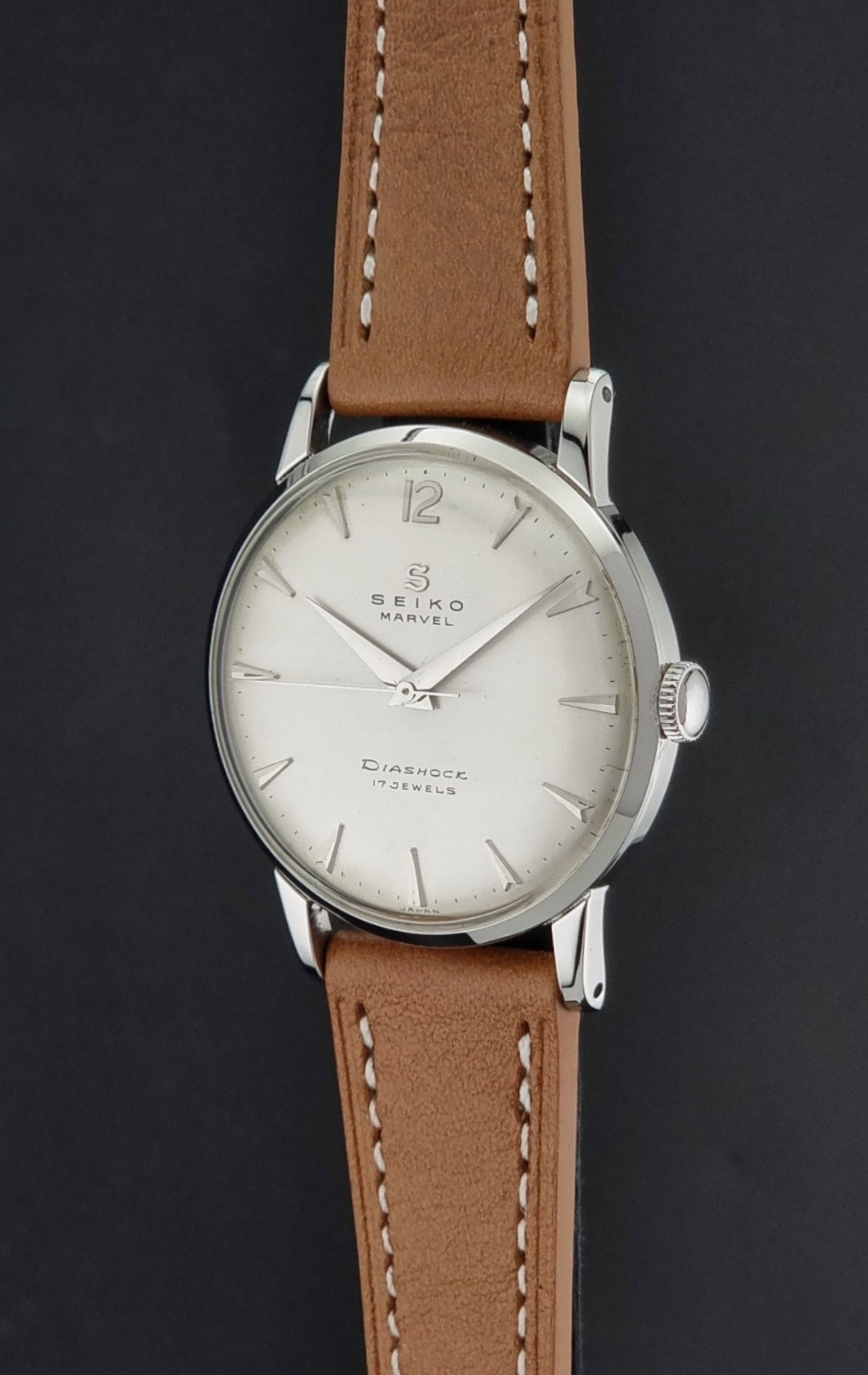 Vintage Seiko Marvel J14004 watch with a brown leather strap on a dark background crown profile view