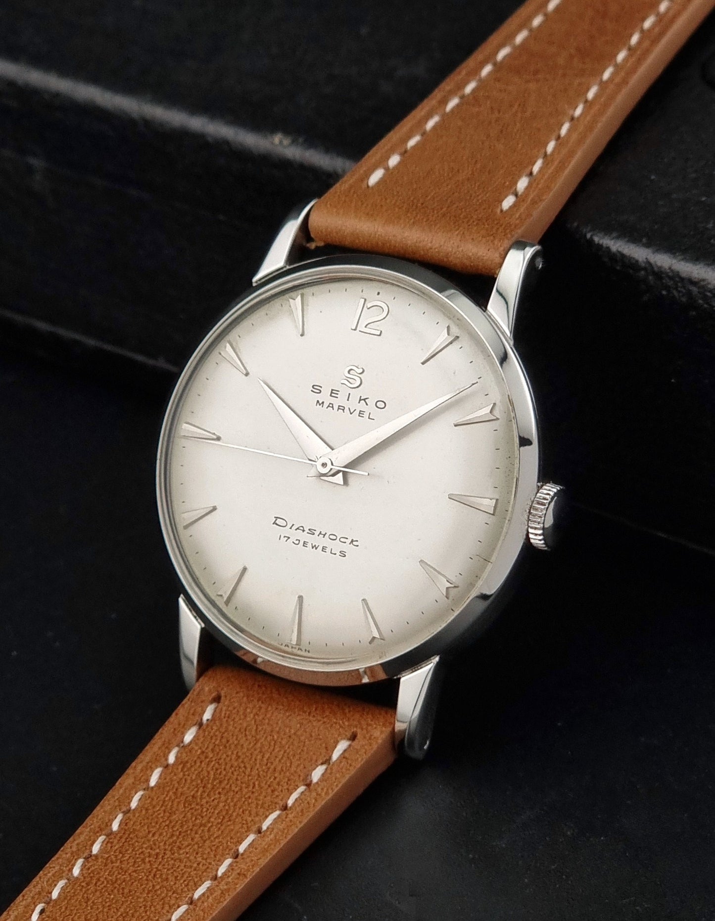 Vintage Seiko Marvel J14004 watch with a brown leather strap on a dark background crown view