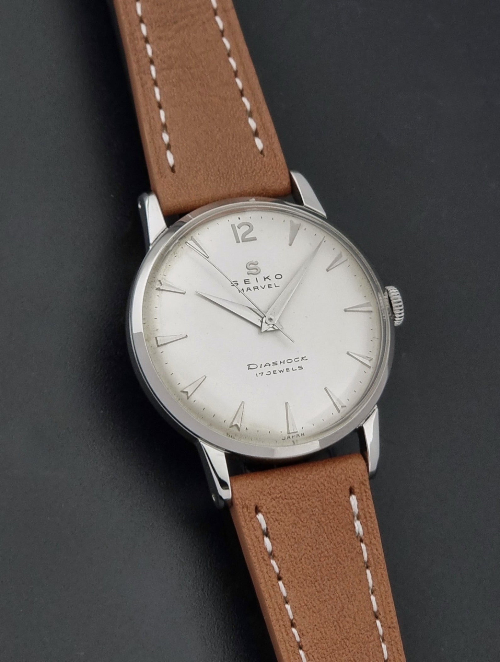 Vintage Seiko Marvel J14004 watch with a brown leather strap on a dark background front view