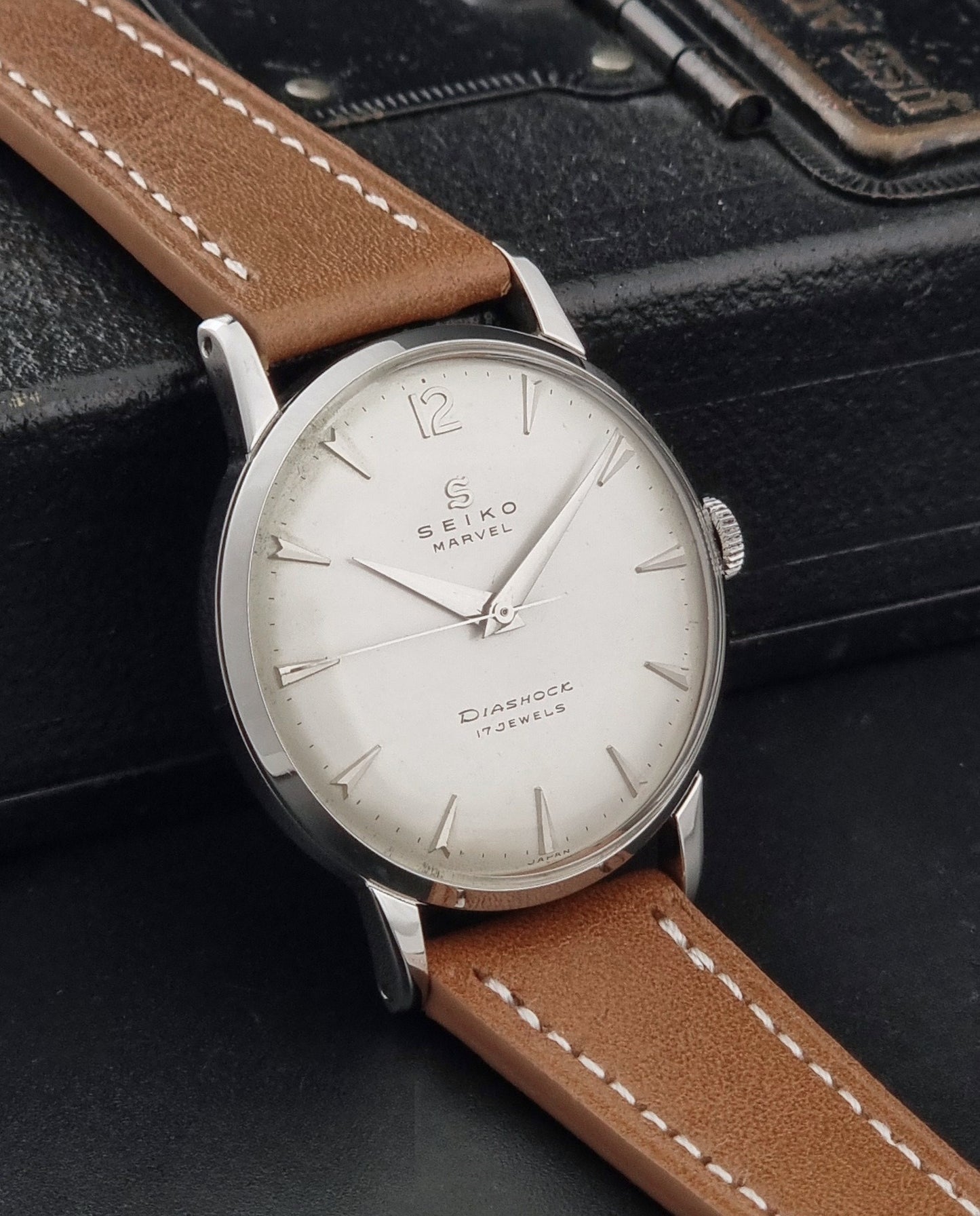 Vintage Seiko Marvel J14004 watch with a brown leather strap on a dark background side view