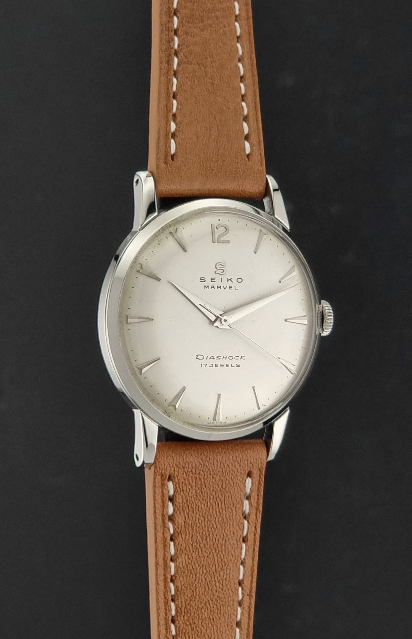 Vintage Seiko Marvel J14004 watch with a brown leather strap on a dark background side profile view