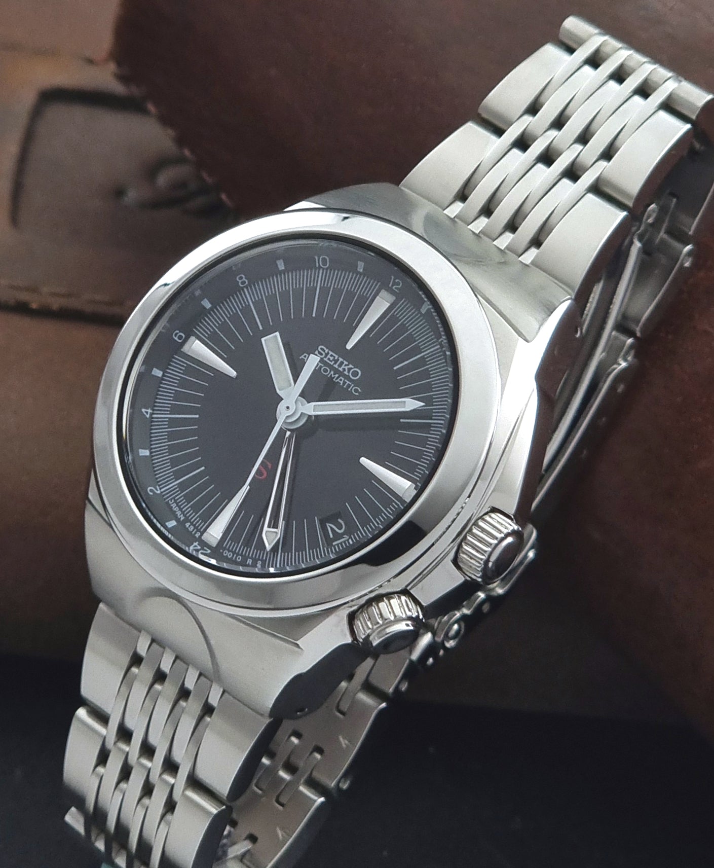 Seiko watch Mechasus SCFF005 GMT 4S12-0010 with a black dial on a gray background crown view