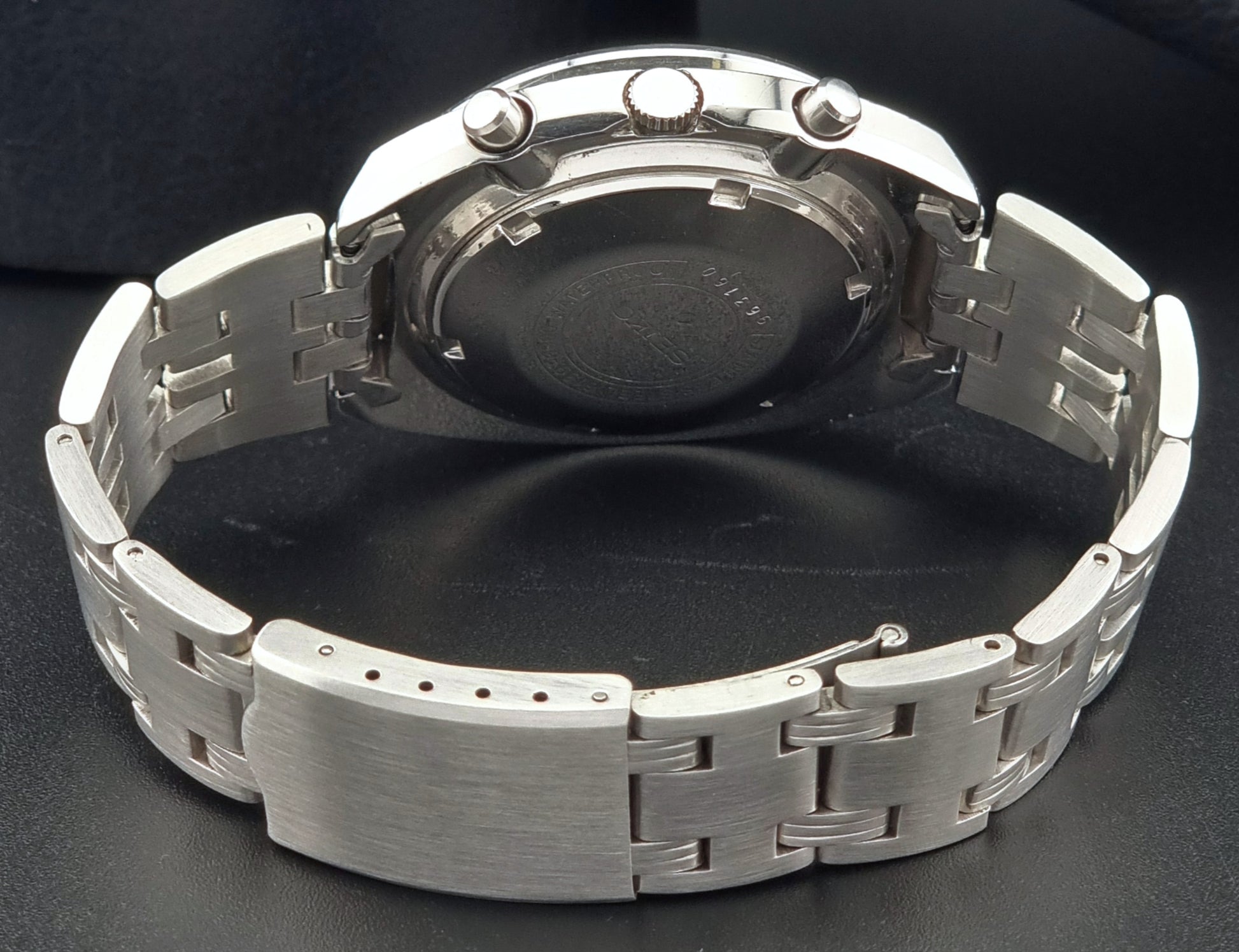 Seiko speedtimer watch  case back and metal bracelet on a dark background