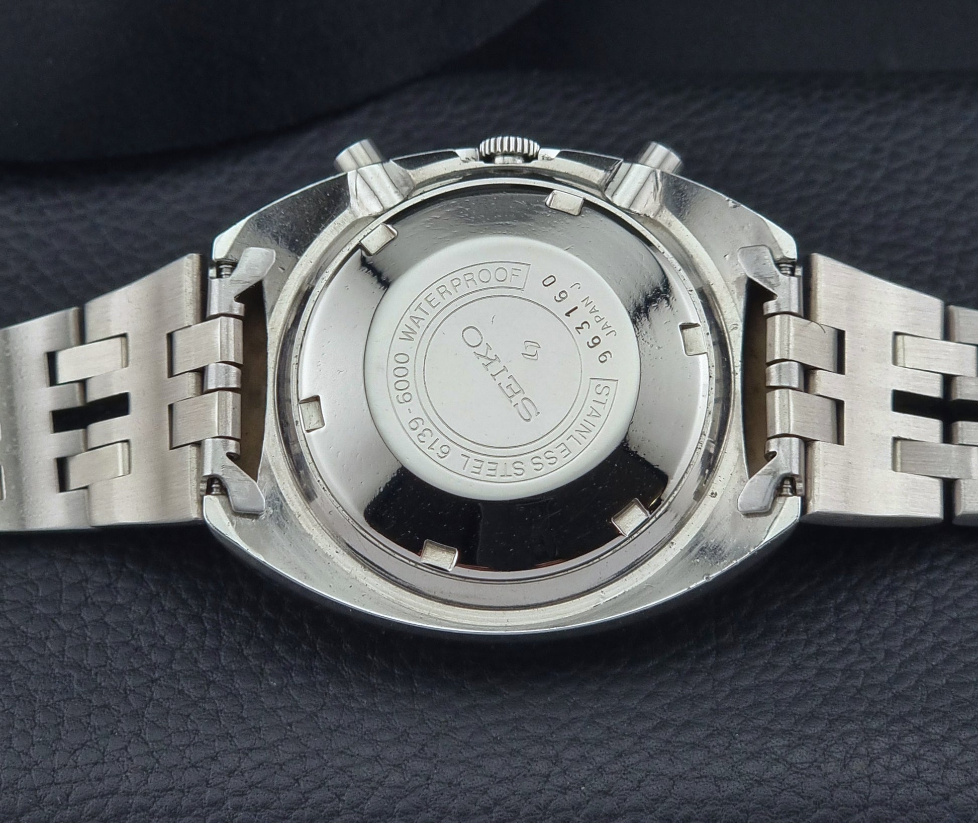 Close-up of a silver watch with Seiko branding on a dark textured surface