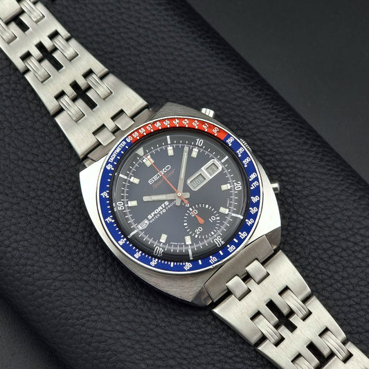 Seiko speedtimer watch with a blue and red bezel on a dark textured background