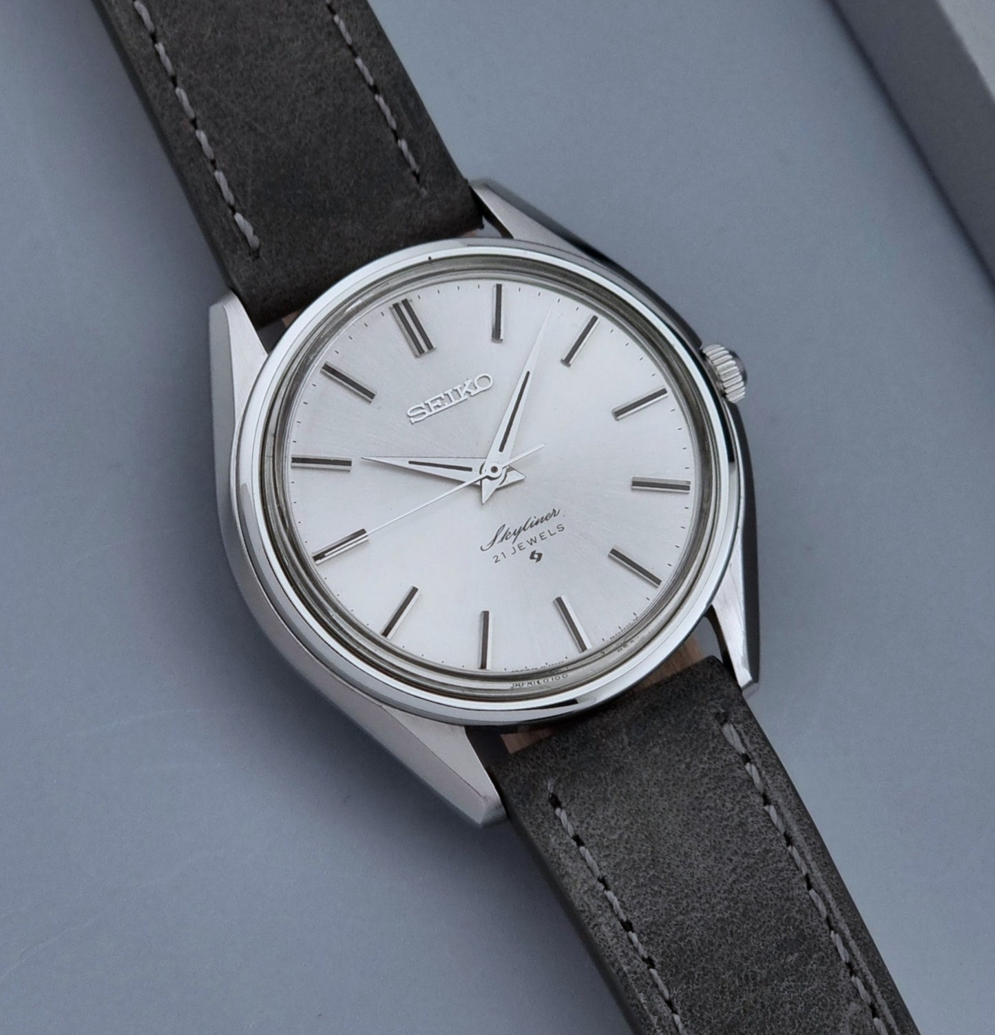 Vintage Seiko Wristwatch Skyliner 6100-8000 with a grey leather strap and silver case on a grey background dial view