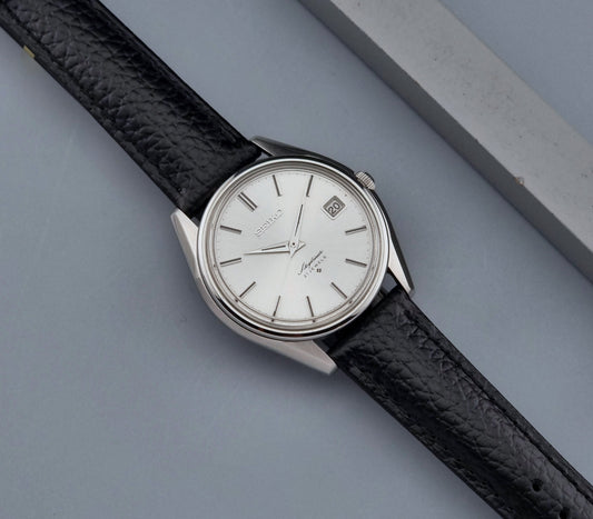 Vintage Seiko Wristwatch Skyliner 6102-8000 with black leather strap and silver case on a light gray background dial