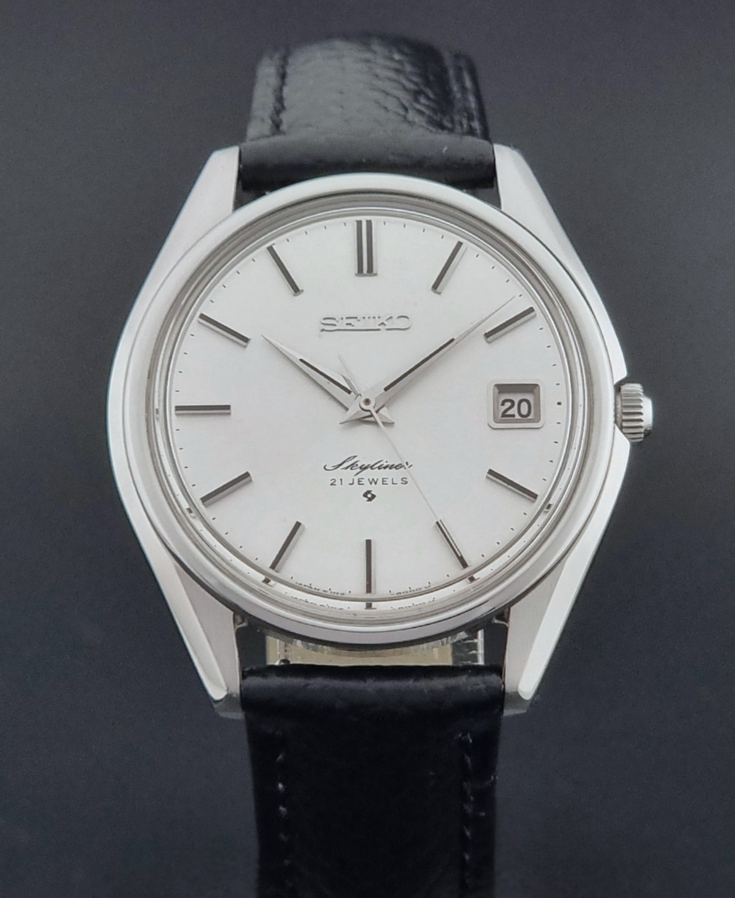 Vintage Seiko Wristwatch Skyliner 6102-8000 with black leather strap and silver case on a light gray background close dial view