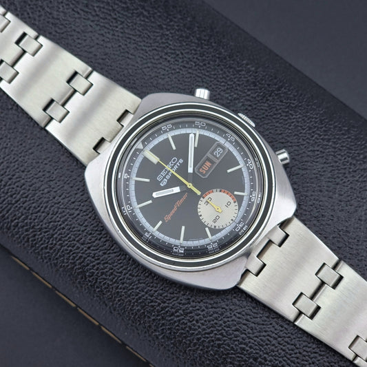 Vintage Seiko 5 sports Speedtimer 6139-7020 wristwatch with a dark face on a textured black background