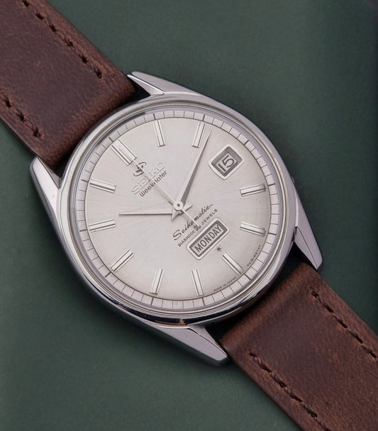 Vintage Seiko watch with brown leather strap and silver case on a green background