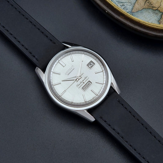 Vintage Seiko Wristwatch Seikomatic Weekdater 6218-8971 with black leather strap on a dark surface dial
