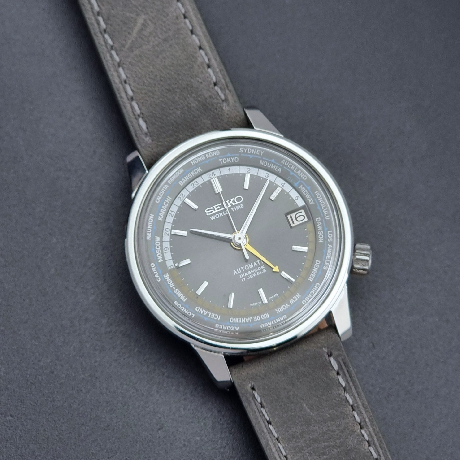 Vintage Seiko Wristwatch World Time 6217-7000 gray leather strap and dark gray dial on a dark background close up