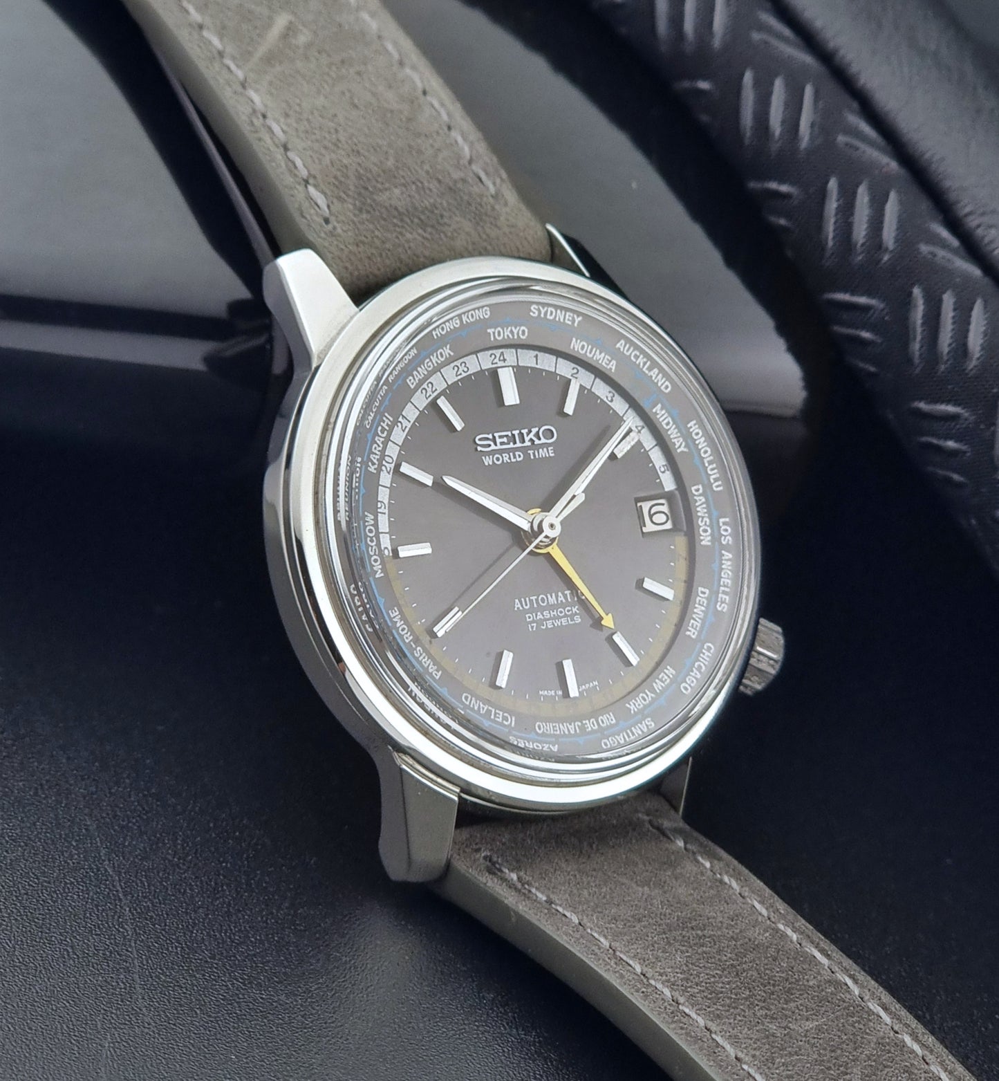 Vintage Seiko Wristwatch World Time 6217-7000 gray leather strap and dark gray dial on a dark background side view