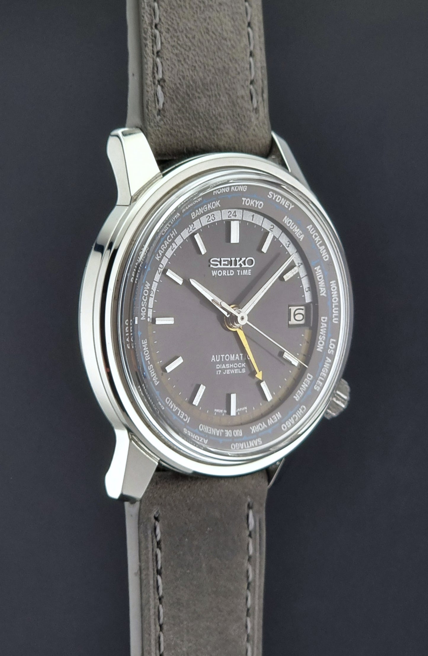 Vintage Seiko Wristwatch World Time 6217-7000 gray leather strap and dark gray dial on a dark background side profile