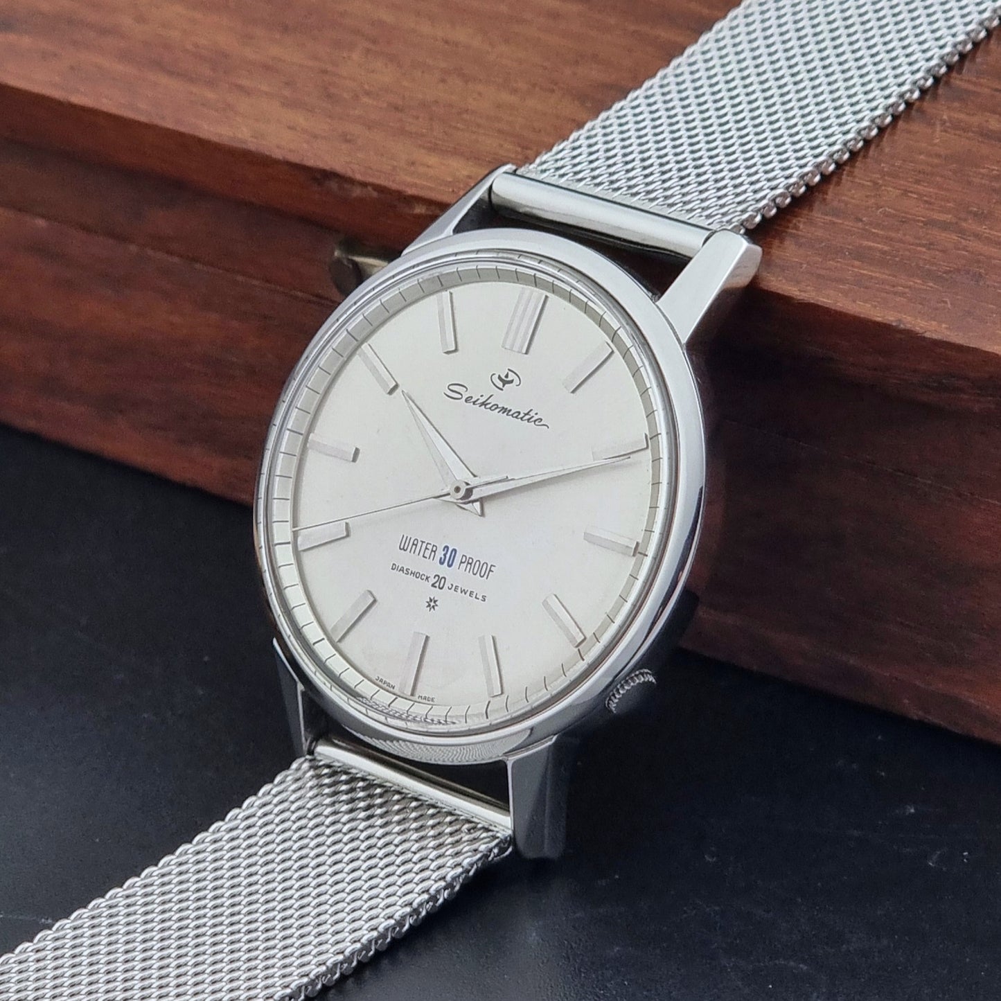 Vintage Seiko Wristwatch Seikomatic J13044E with mesh strap on a dark background crown view