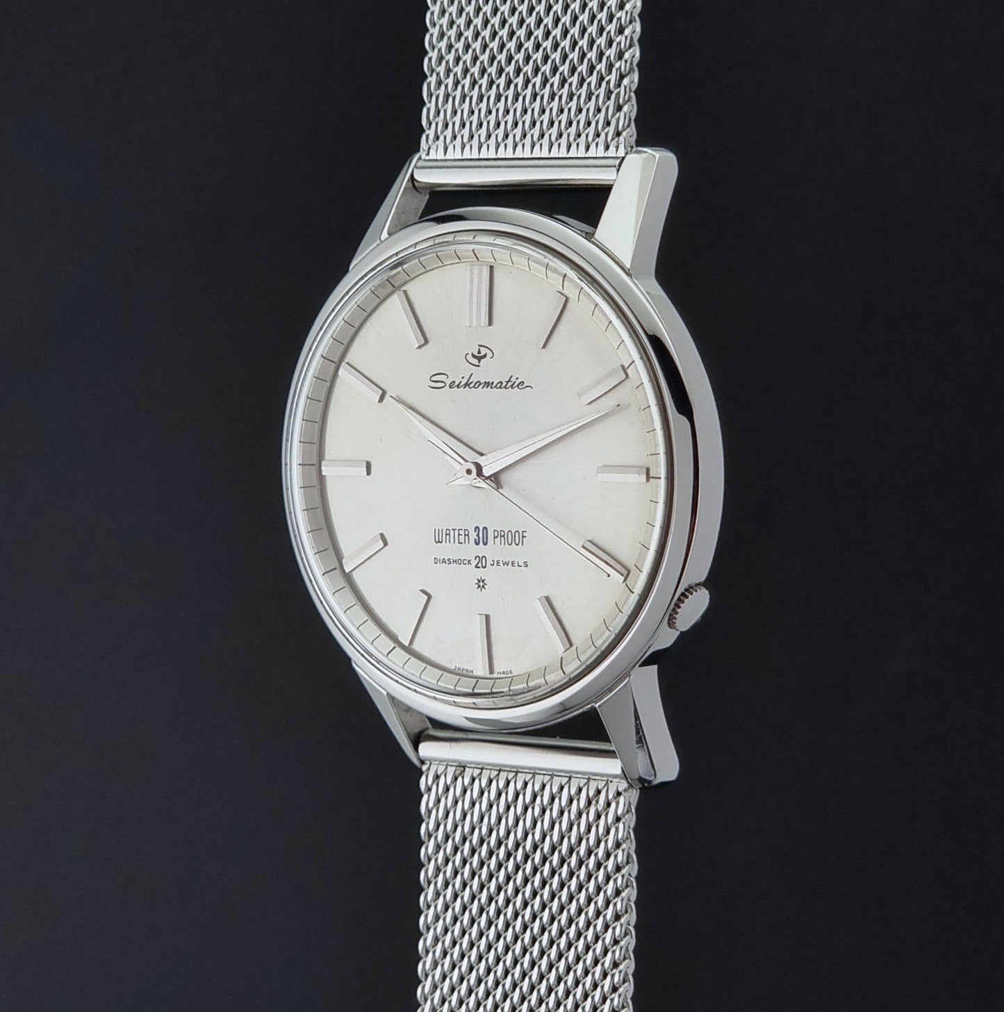 Vintage Seiko Wristwatch Seikomatic J13044E with mesh strap on a dark background crown profile view