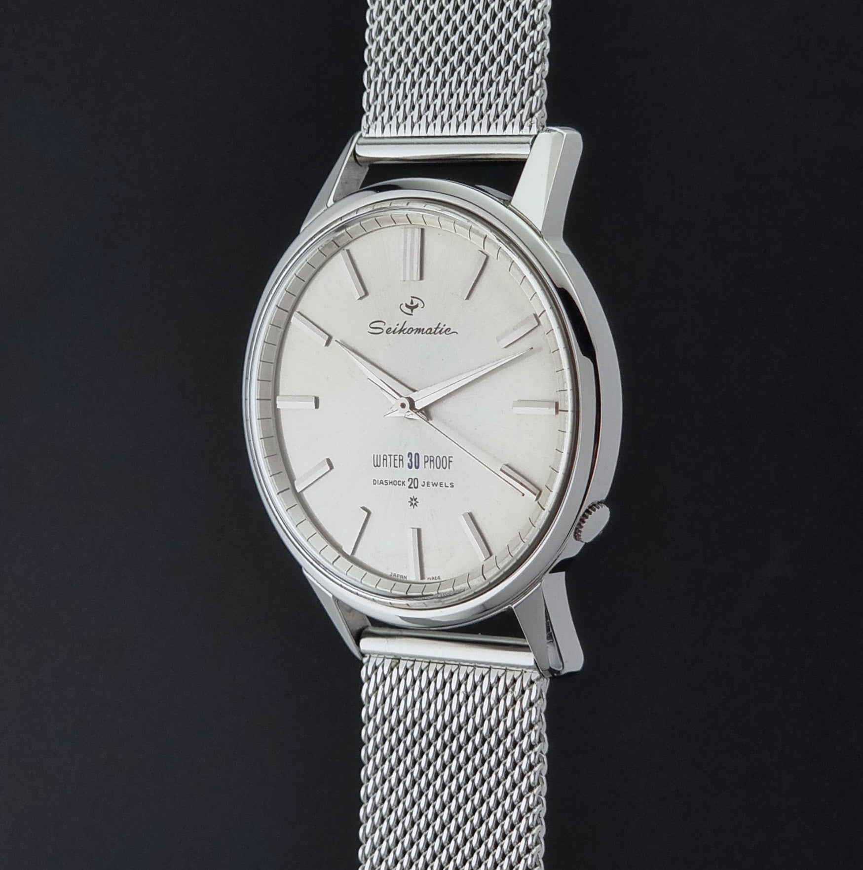 Vintage Seiko Wristwatch Seikomatic J13044E with mesh strap on a dark background crown profile view