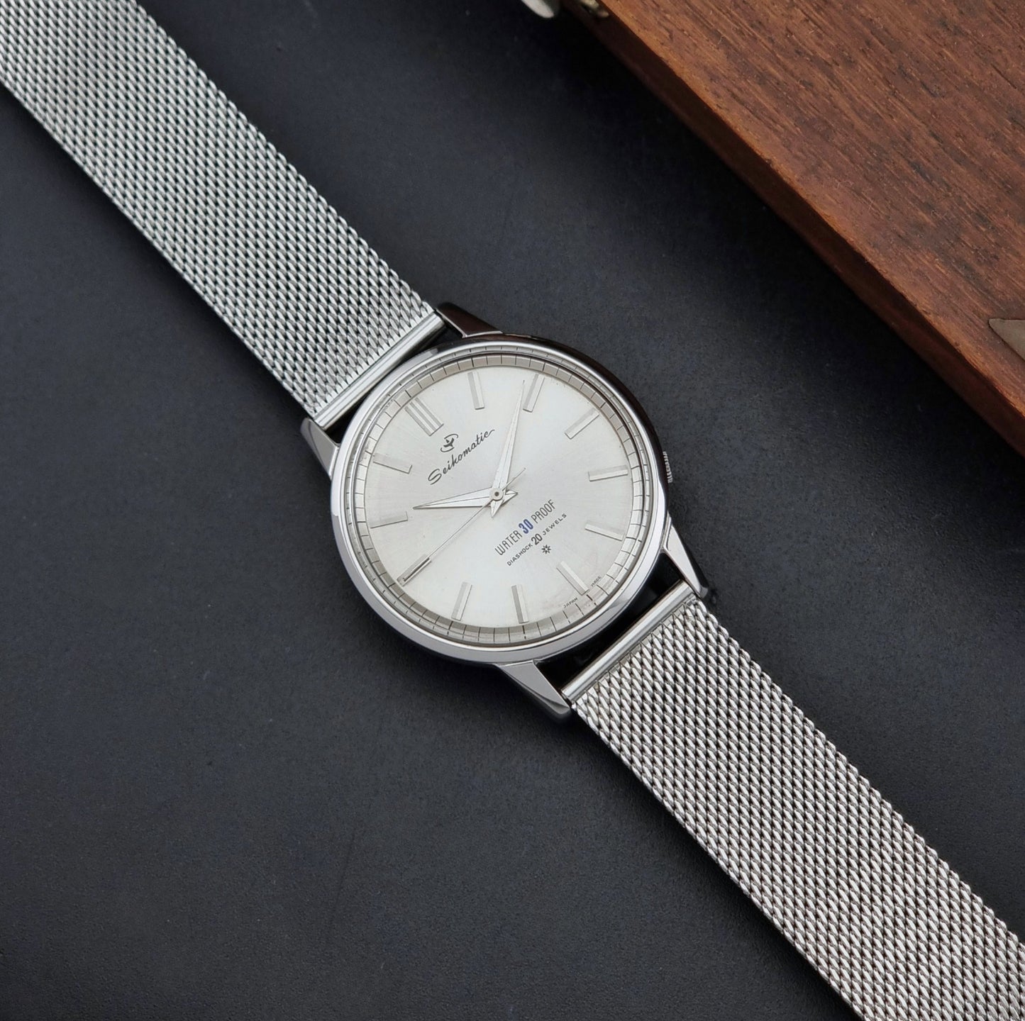 Vintage Seiko Wristwatch Seikomatic J13044E with mesh strap on a dark background dial