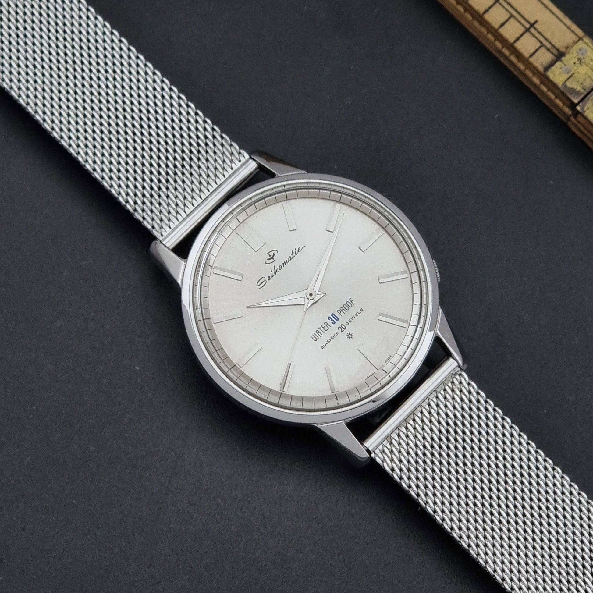 Vintage Seiko Wristwatch Seikomatic J13044E with mesh strap on a dark background close up dial view