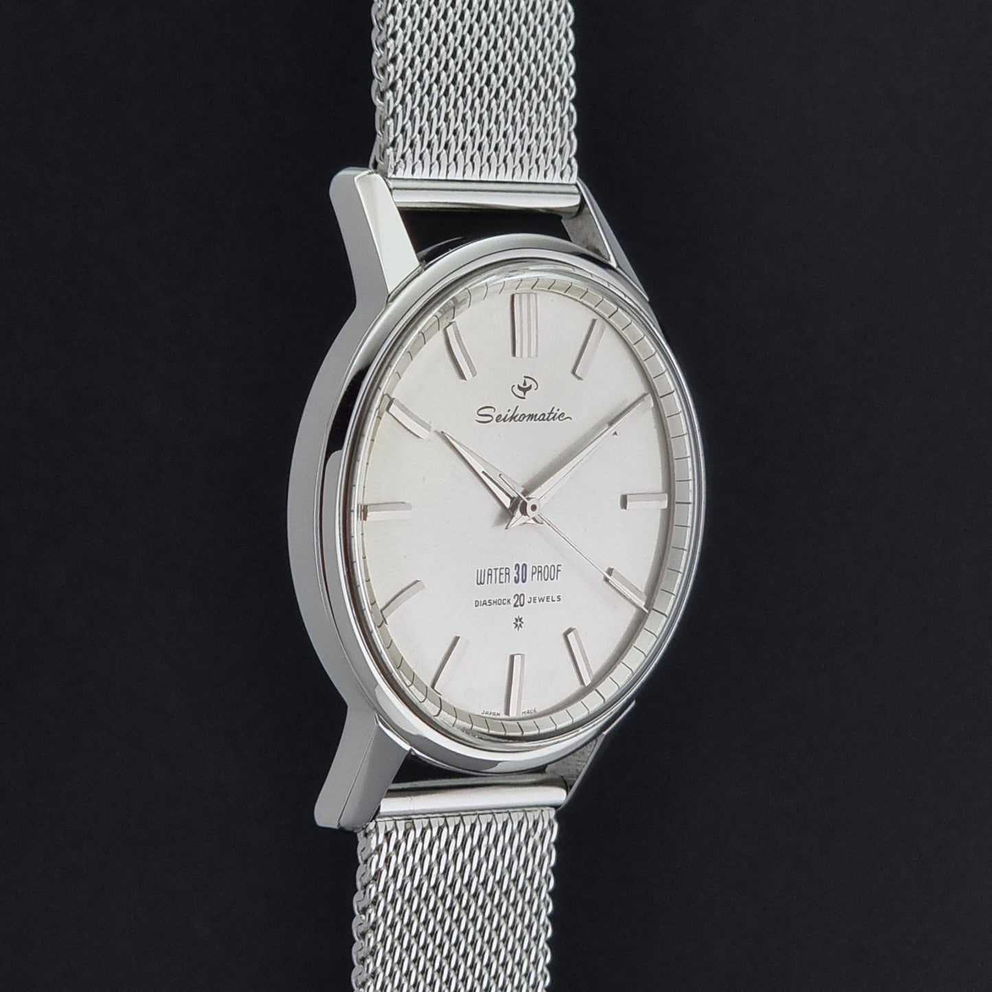 Vintage Seiko Wristwatch Seikomatic J13044E with mesh strap on a dark background side profile view