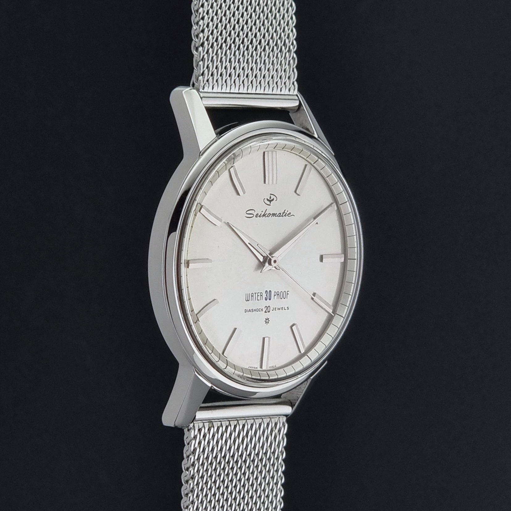 Vintage Seiko Wristwatch Seikomatic J13044E with mesh strap on a dark background side profile view