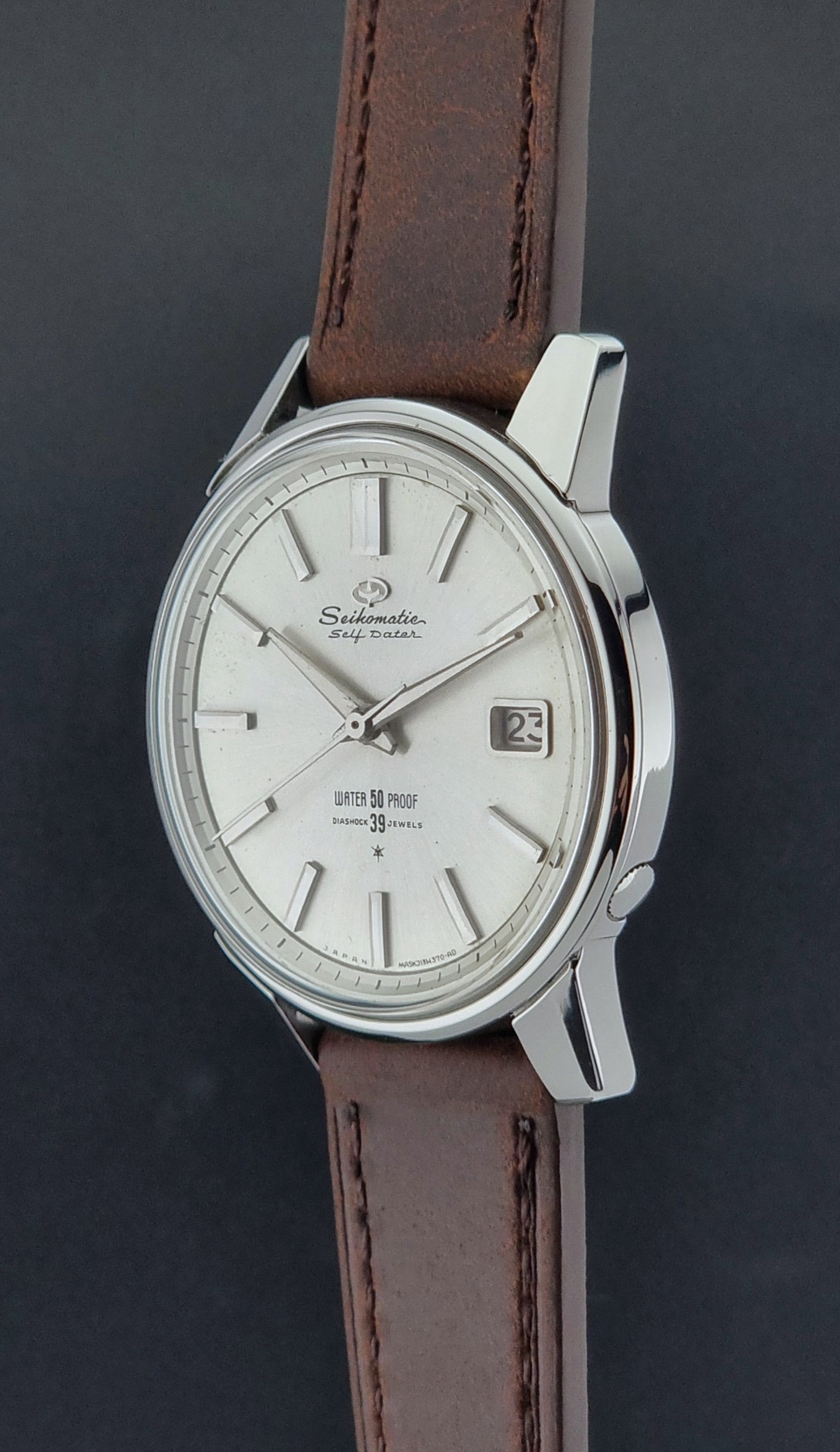 Vintage Seiko Wristwatch Seikomatic J13085 brown leather strap on a dark textured surface crown profile view