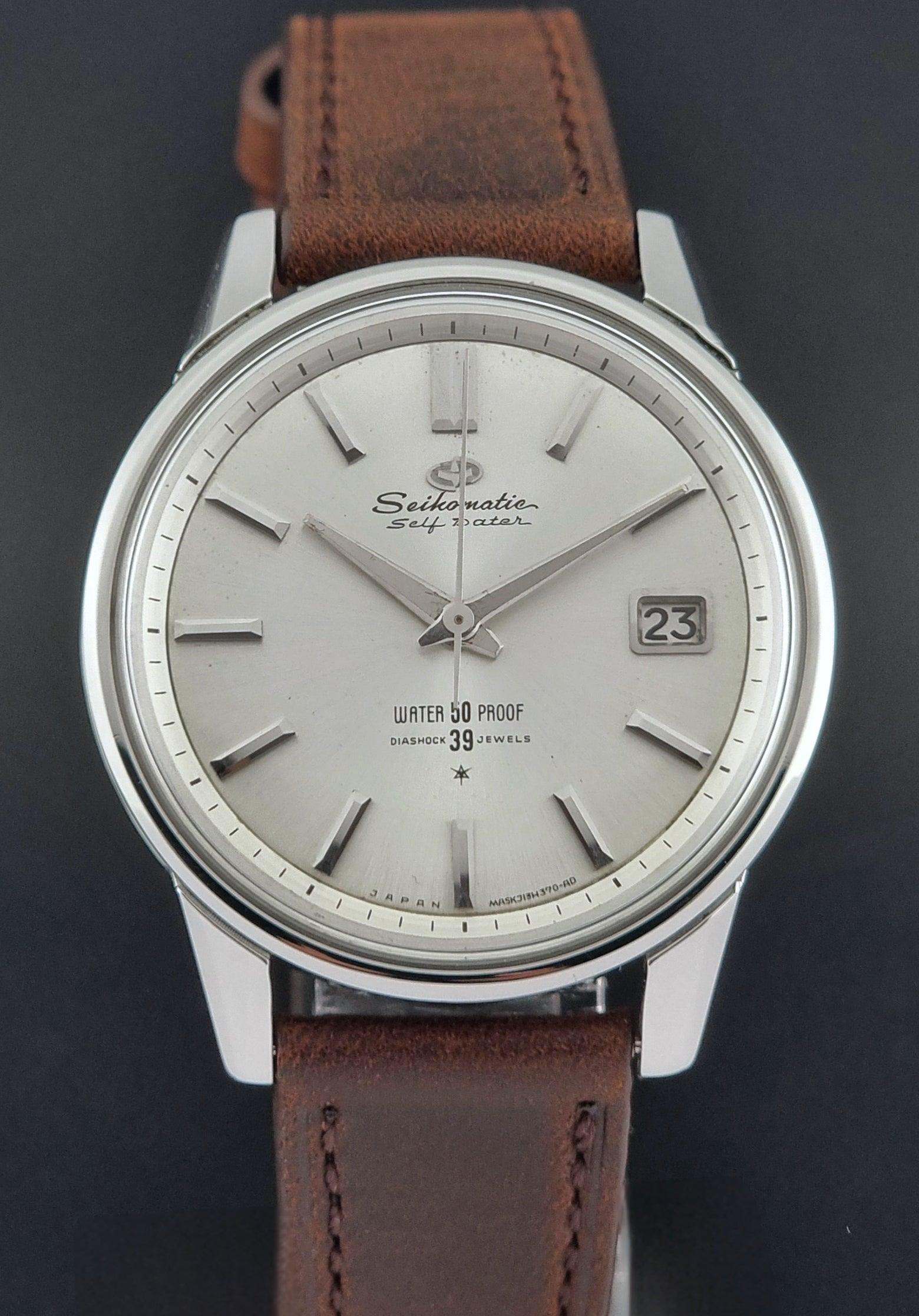 Vintage Seiko Wristwatch Seikomatic J13085 brown leather strap on a dark textured surface dial view