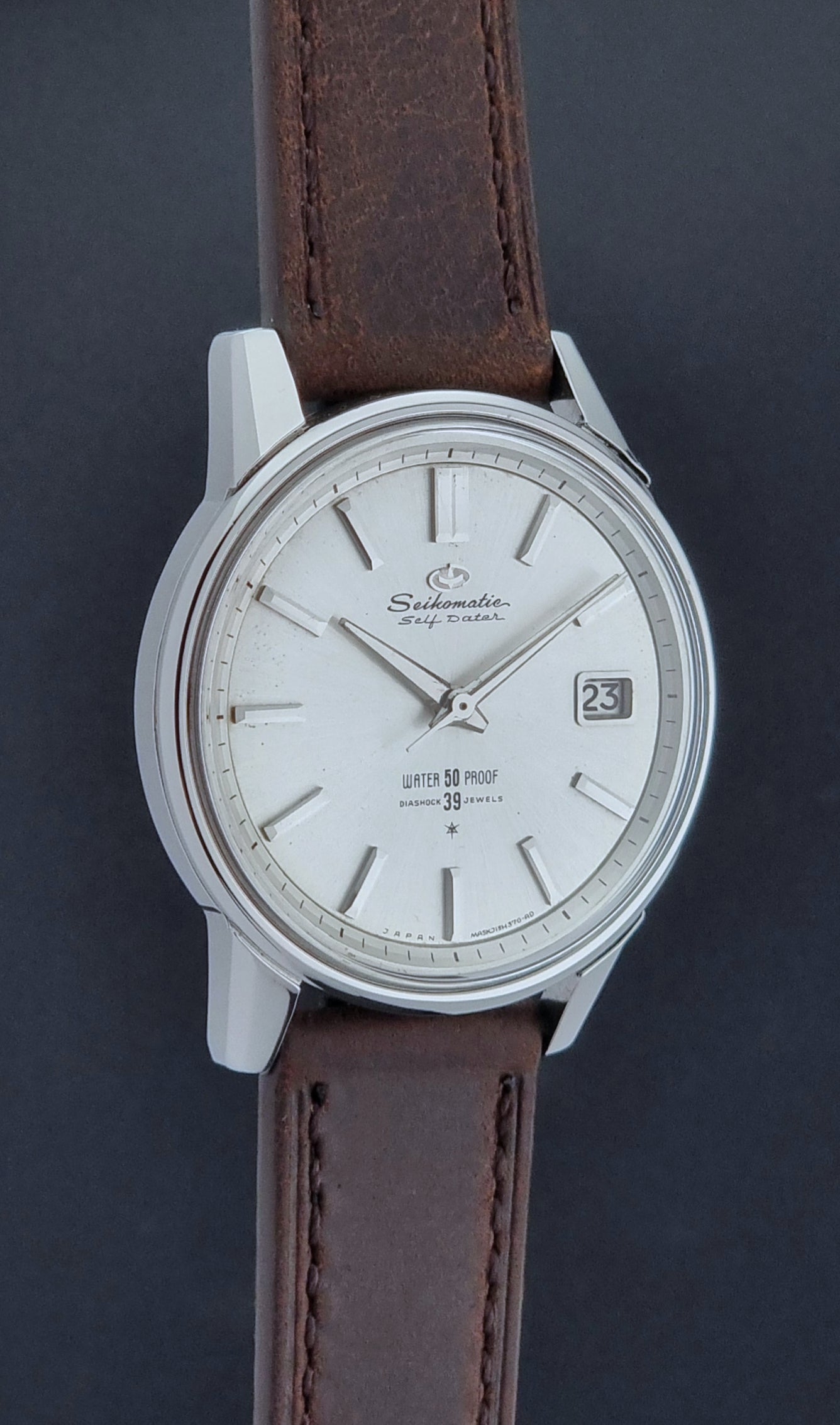 Vintage Seiko Wristwatch Seikomatic J13085 brown leather strap on a dark textured surface side profile view