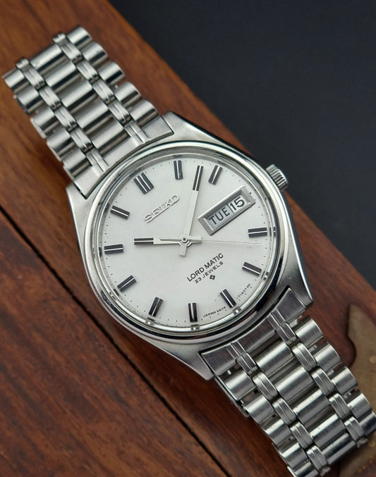 Silver Seiko watch with a white face on a wooden surface