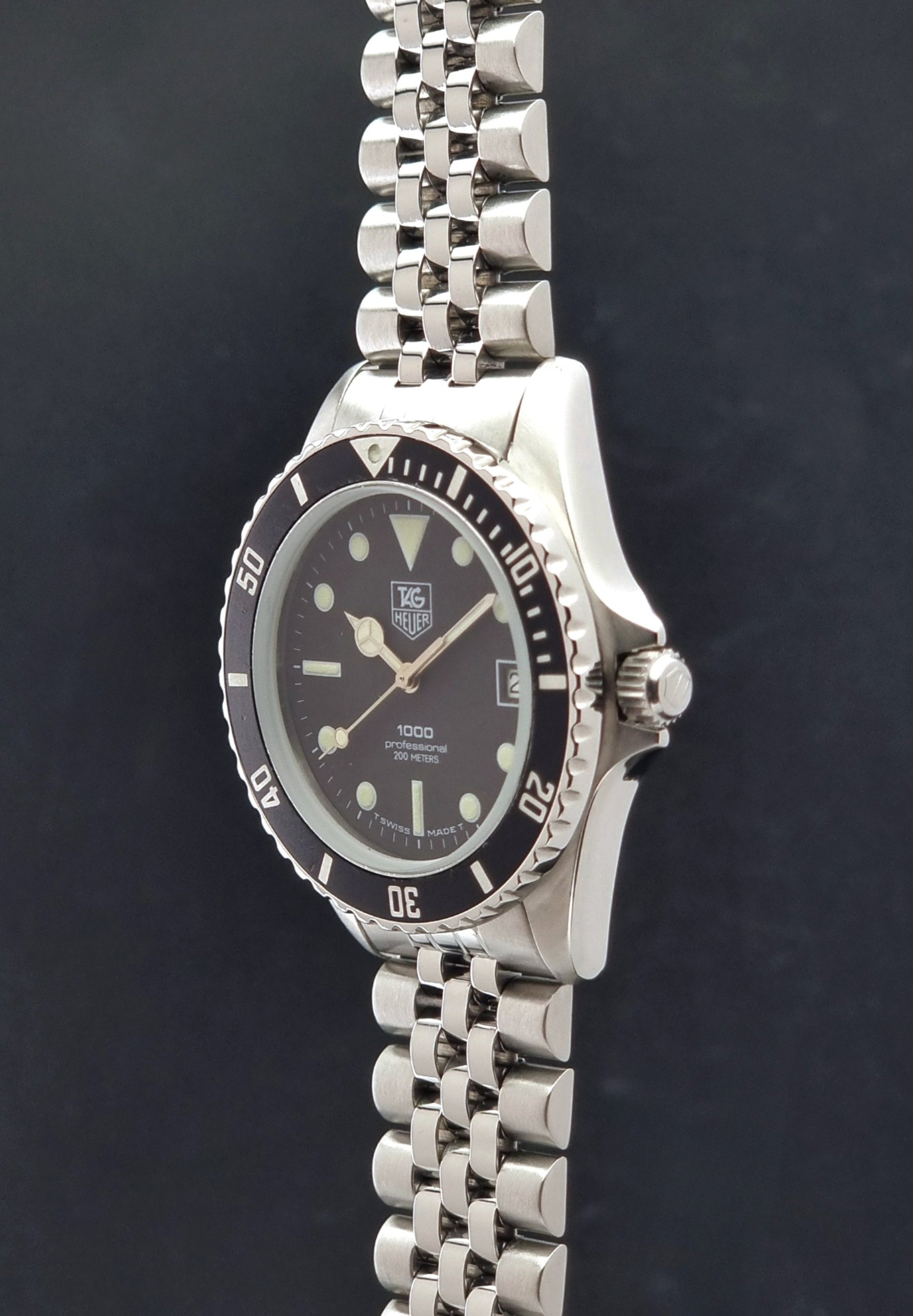Vintage Tag Heuer Wristwatch Professional 1000 Quartz 980.013N with a black dial on a dark background crown profile view