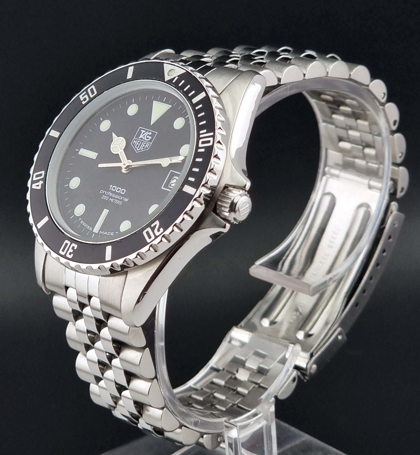 Vintage Tag Heuer Wristwatch Professional 1000 Quartz 980.013N with a black dial on a dark background close crown view