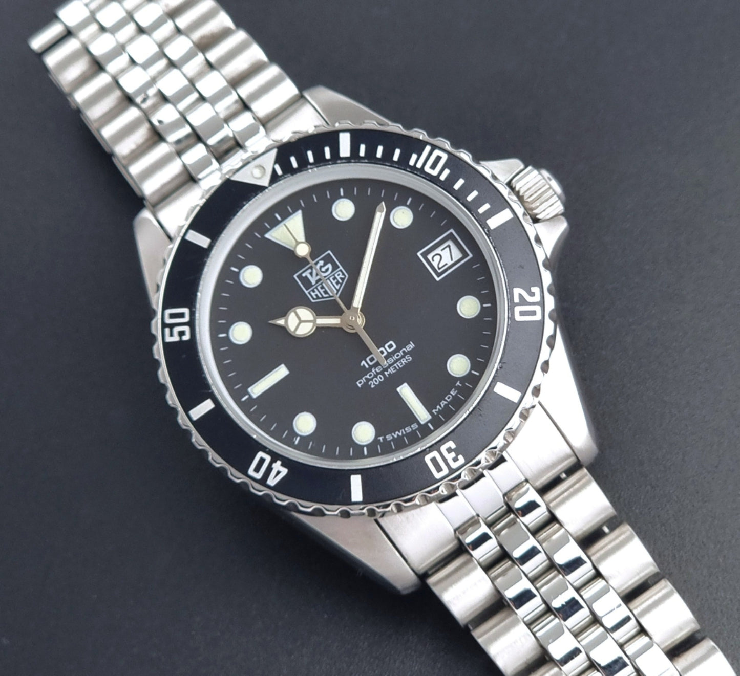 Vintage Tag Heuer Wristwatch Professional 1000 Quartz 980.013N with a black dial on a dark background front view