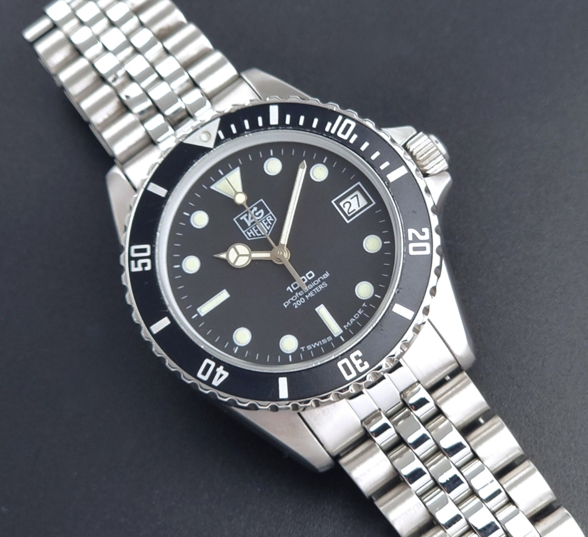 Vintage Tag Heuer Wristwatch Professional 1000 Quartz 980.013N with a black dial on a dark background front view