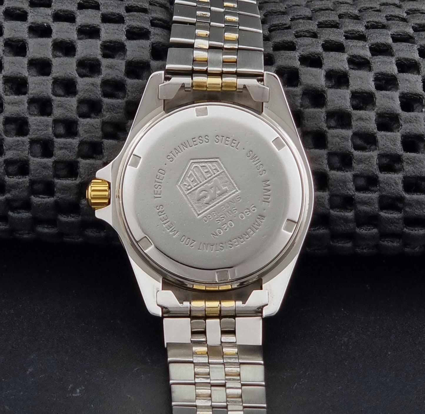 Vintage Tag Heuer watch Professional Quartz 1000 Diver 980.020N with silver and gold band on a dark background case back view