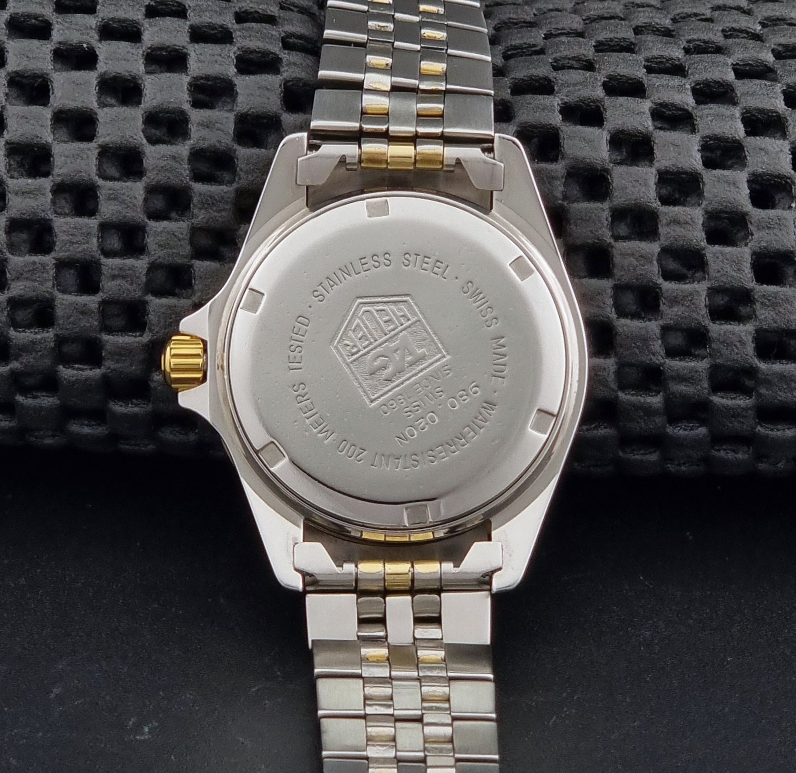Vintage Tag Heuer watch Professional Quartz 1000 Diver 980.020N with silver and gold band on a dark background case back view