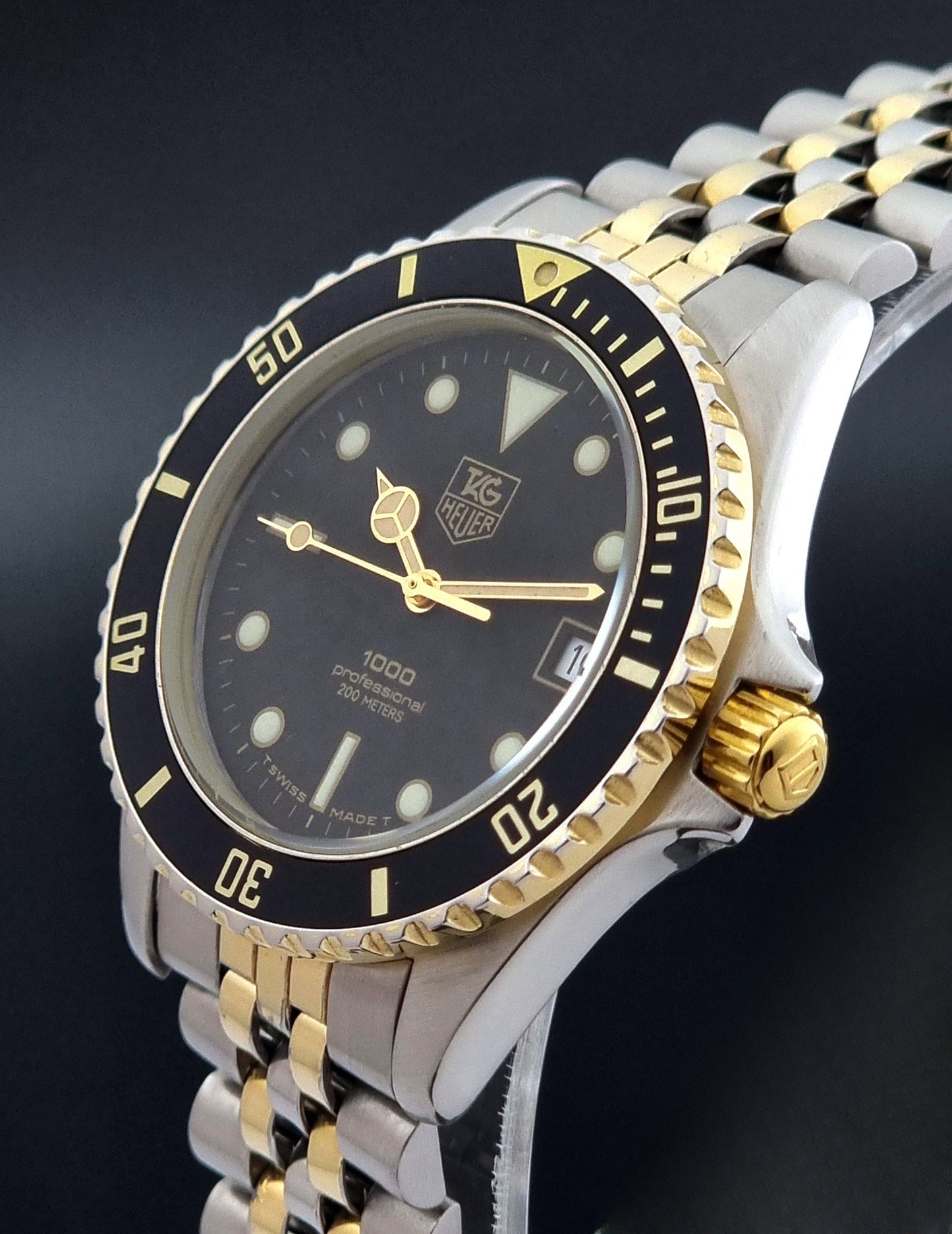 Vintage Tag Heuer watch Professional Quartz 1000 Diver 980.020N with silver and gold band on a dark background crown profile view