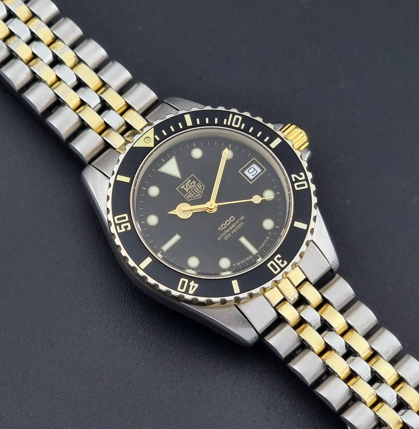 Vintage Tag Heuer watch Professional Quartz 1000 Diver 980.020N with silver and gold band on a dark background close up dial view