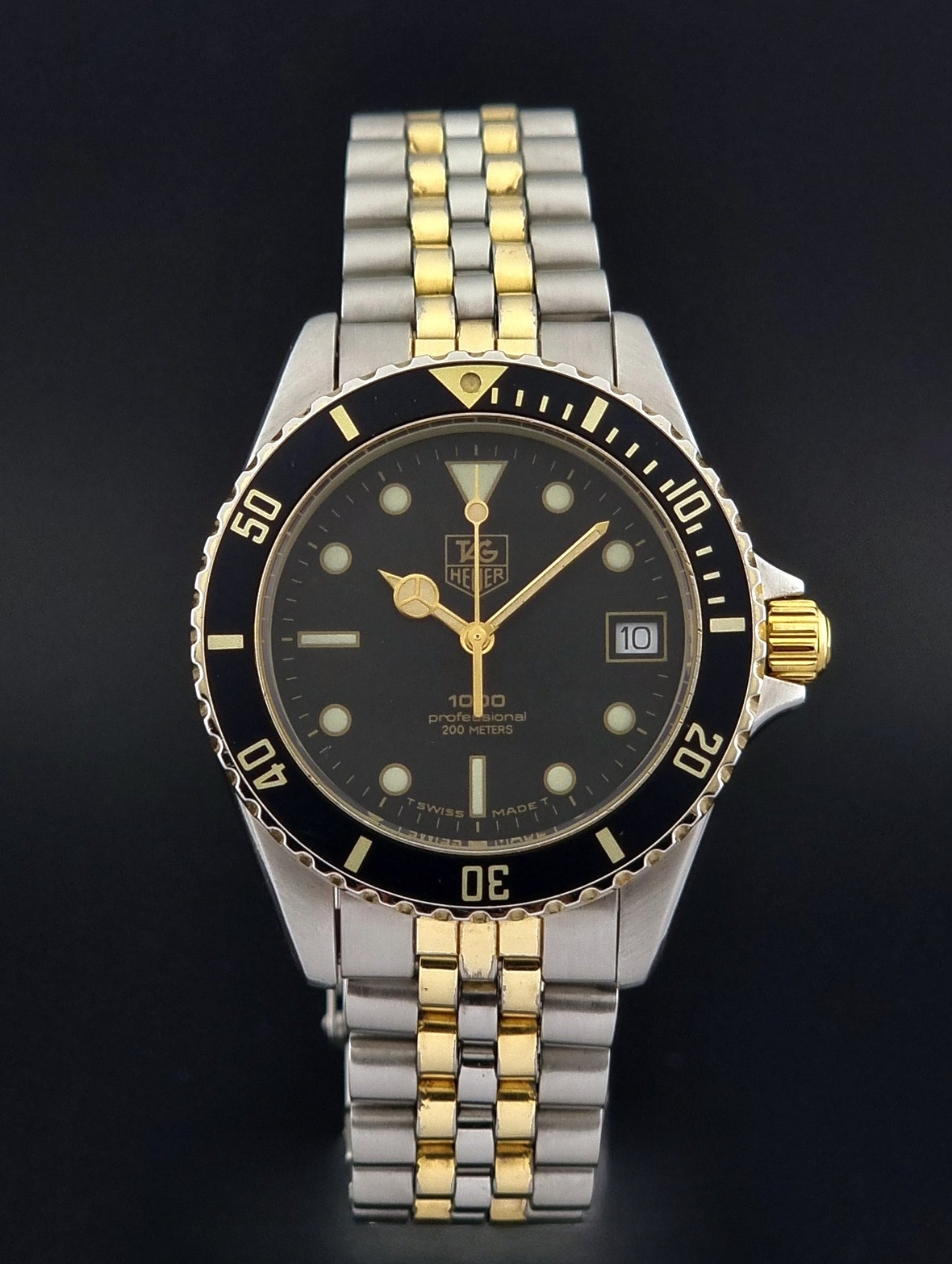 Vintage Tag Heuer watch Professional Quartz 1000 Diver 980.020N with silver and gold band on a dark background close dial view