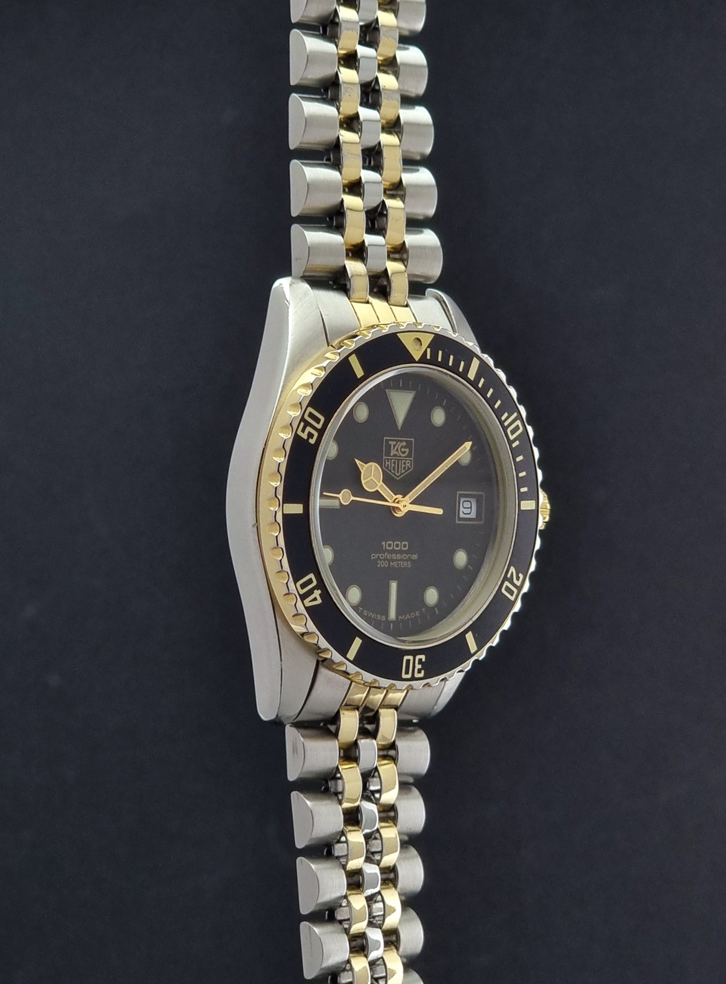 Vintage Tag Heuer watch Professional Quartz 1000 Diver 980.020N with silver and gold band on a dark background close side view