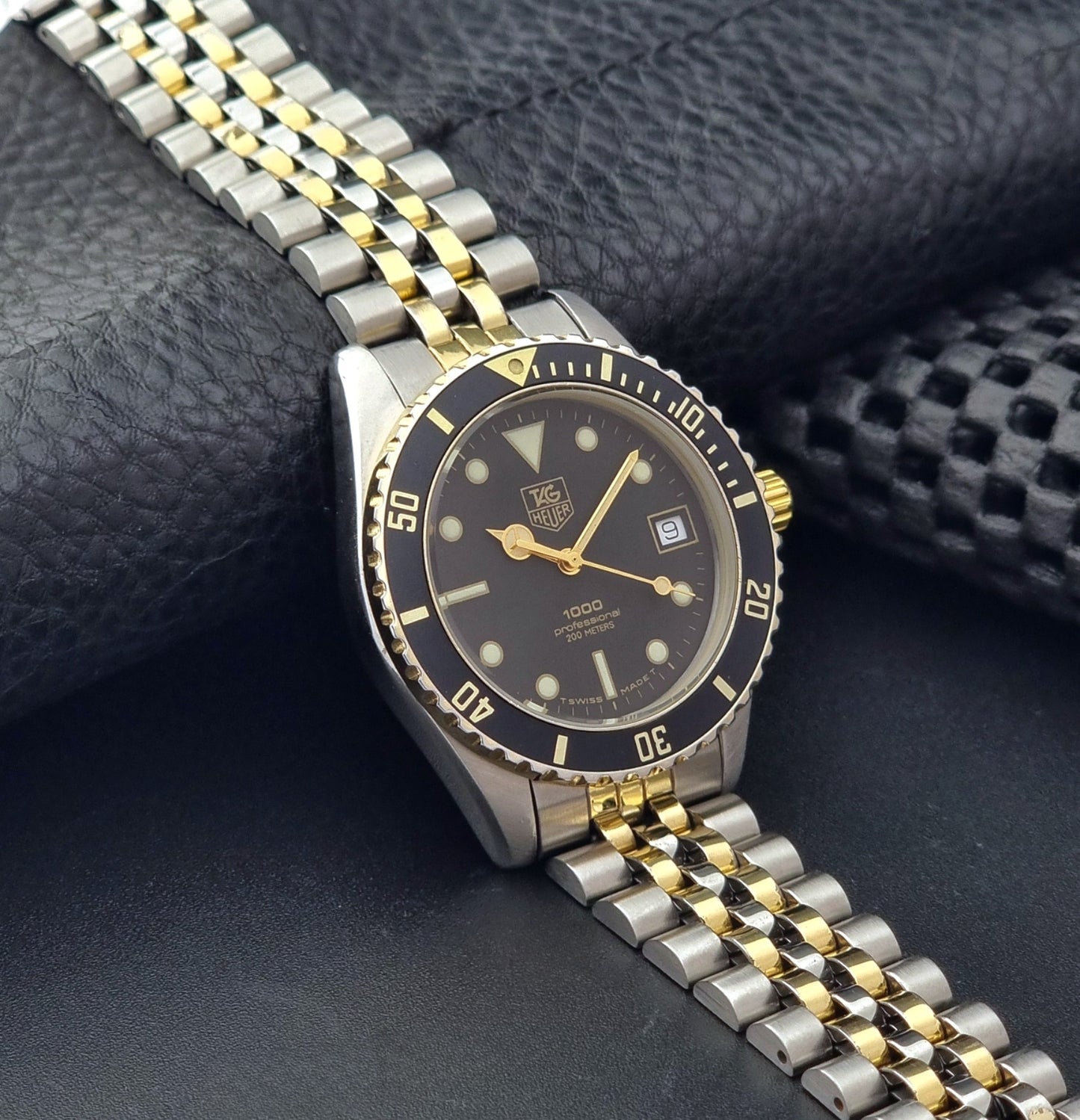 Vintage Tag Heuer watch Professional Quartz 1000 Diver 980.020N with silver and gold band on a dark background side view