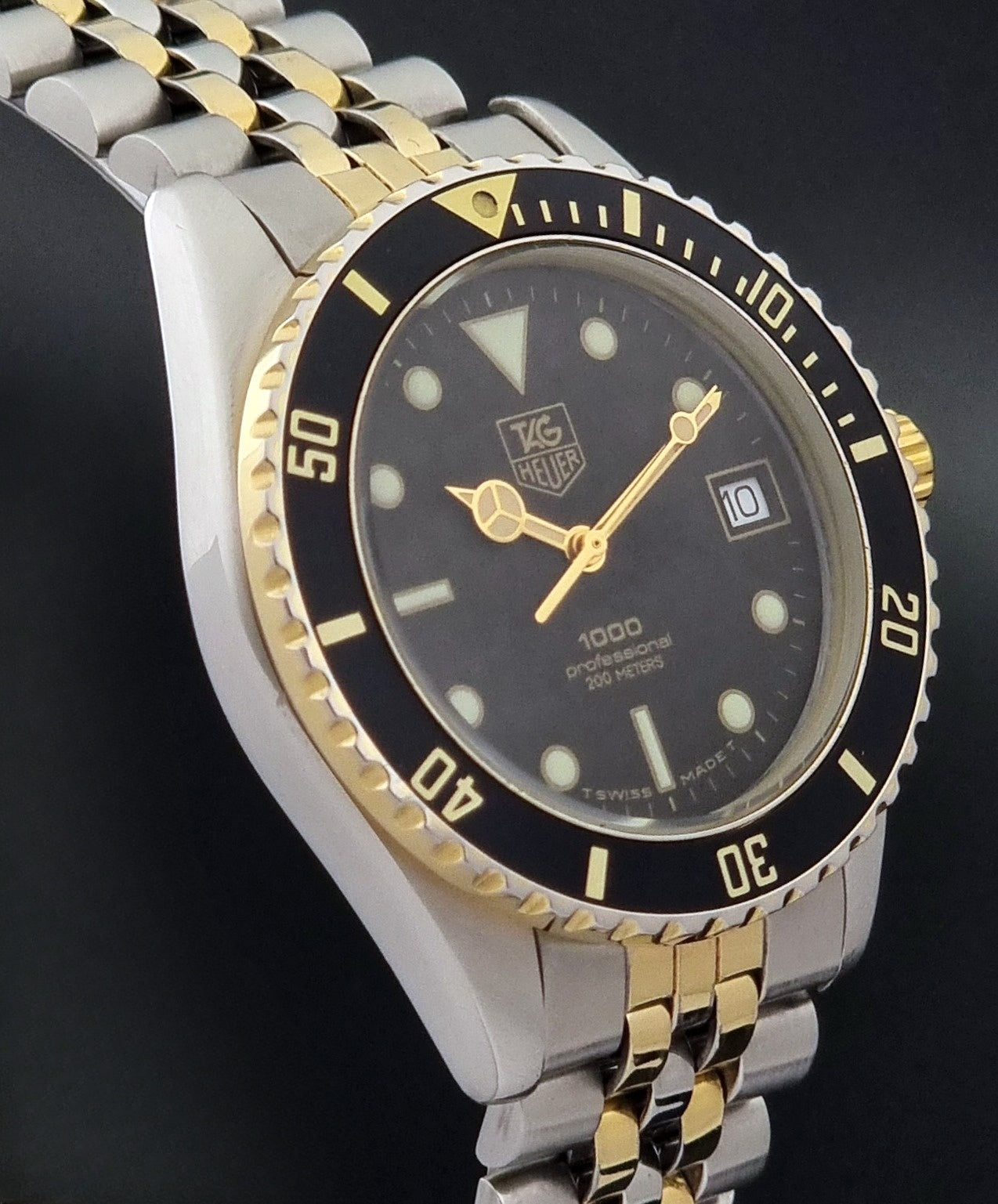 Vintage Tag Heuer watch Professional Quartz 1000 Diver 980.020N with silver and gold band on a dark background side profile view