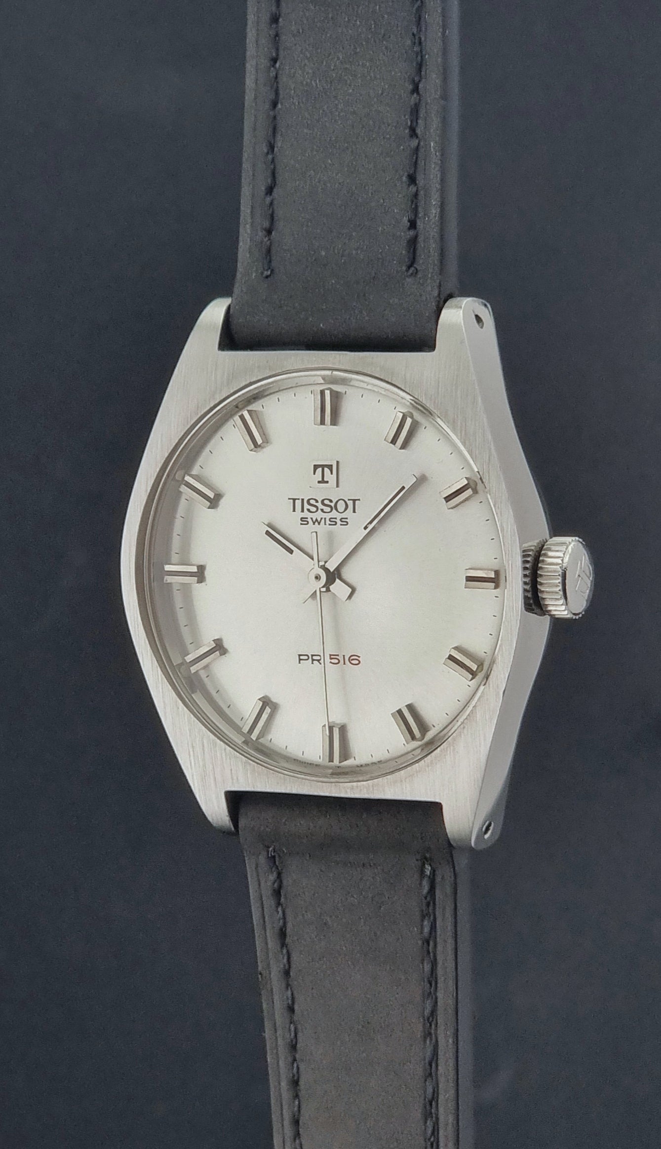 Vintage Tissot Wristwatch 41620 PR 516 with black leather strap on a grey surface crown profile view