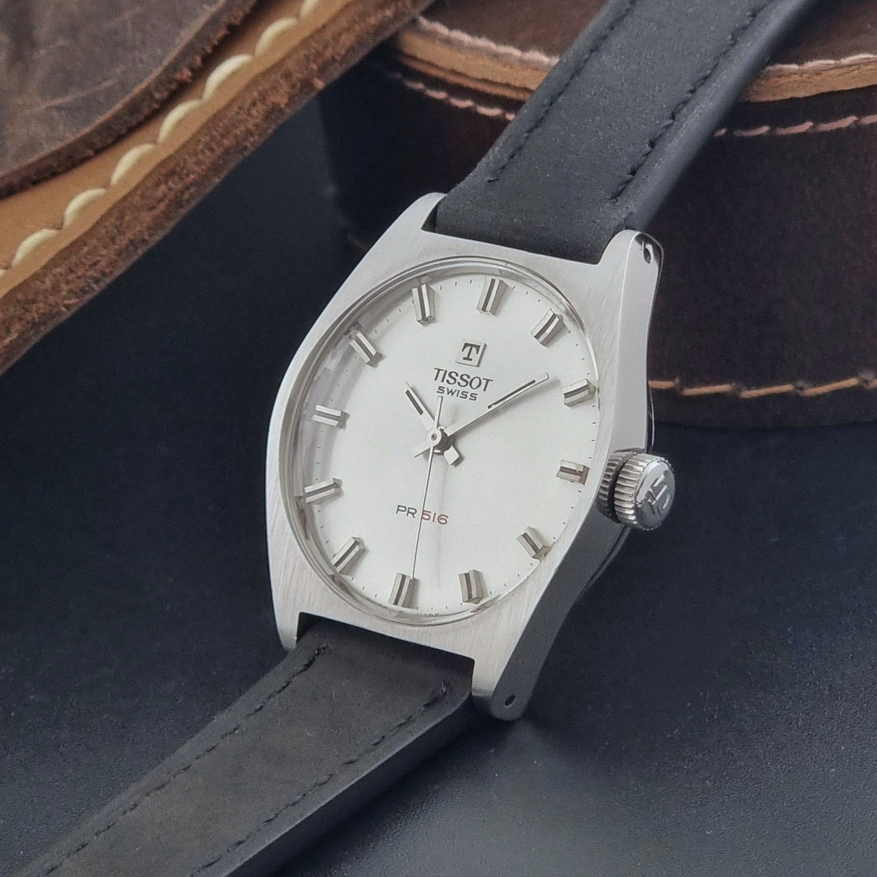 Vintage Tissot Wristwatch 41620 PR 516 with black leather strap on a grey surface crown view