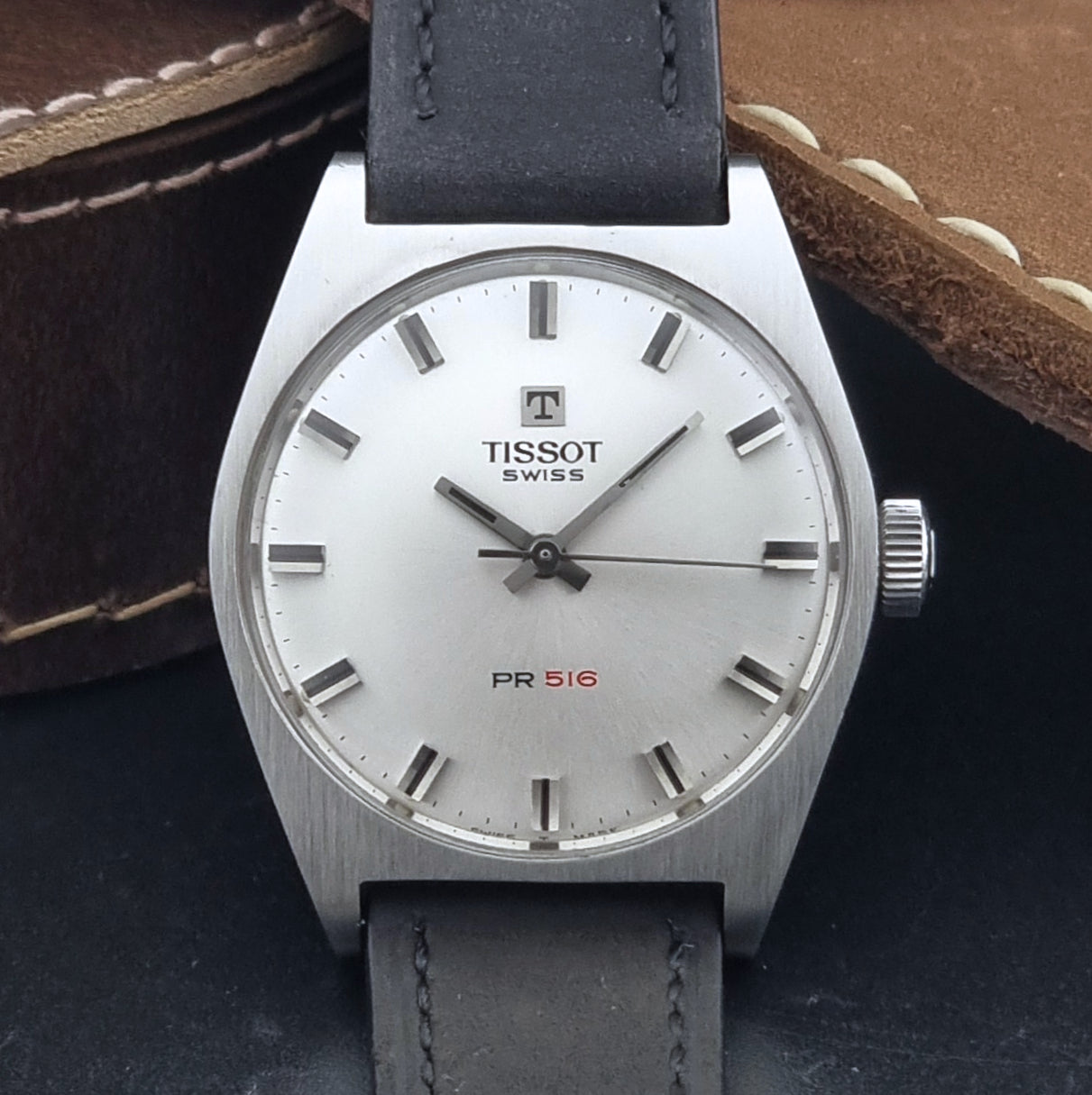 Vintage Tissot Wristwatch 41620 PR 516 with black leather strap on a grey surface front view